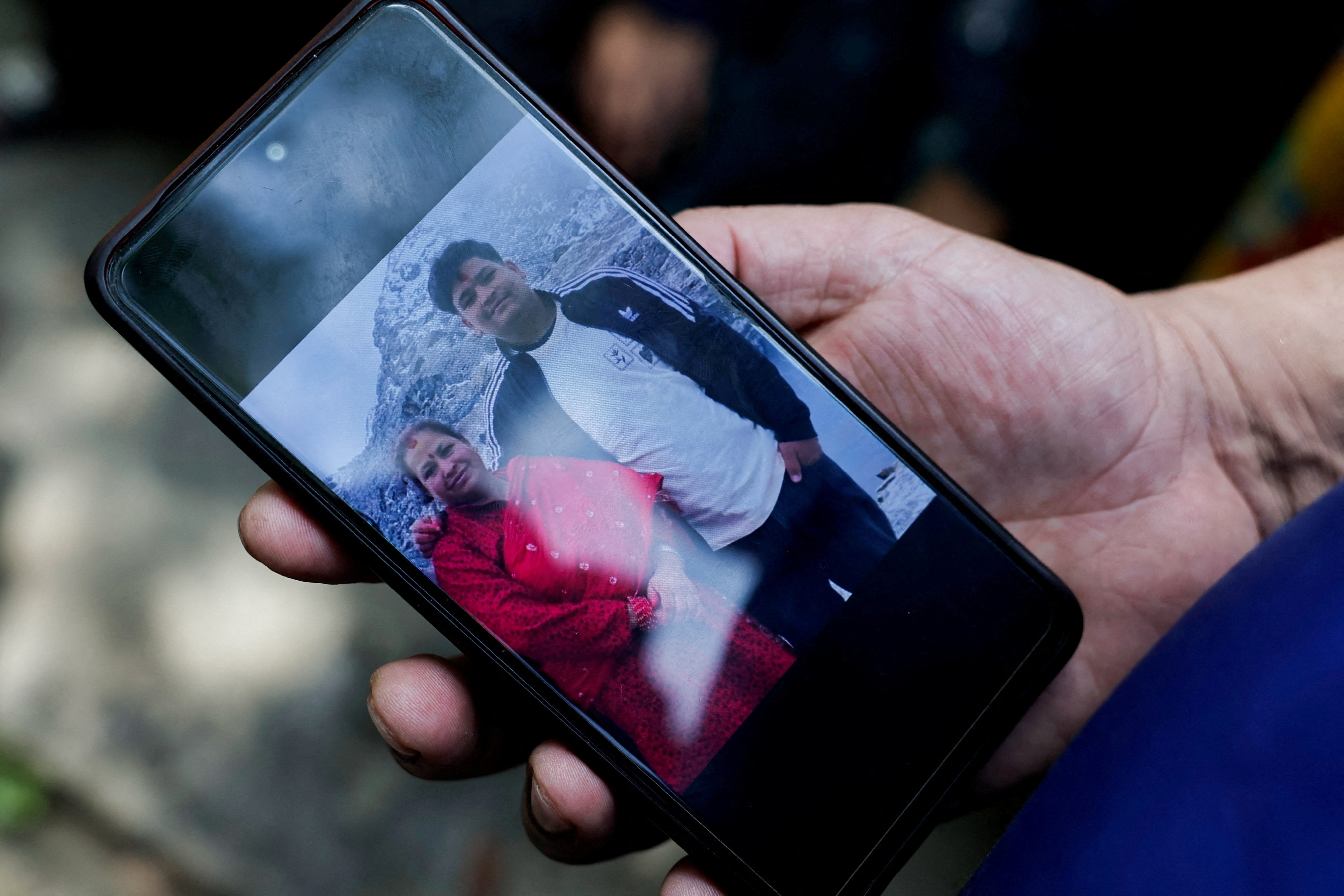 A man shows a photo of his missing family members outside the Maithili Barrack, an army training centre, which serves as a primary base to airlift survivors from Rasuwa following flash floods and mudslide at Trishuli in Nuwakot district, Nepal, August 27, 2026.