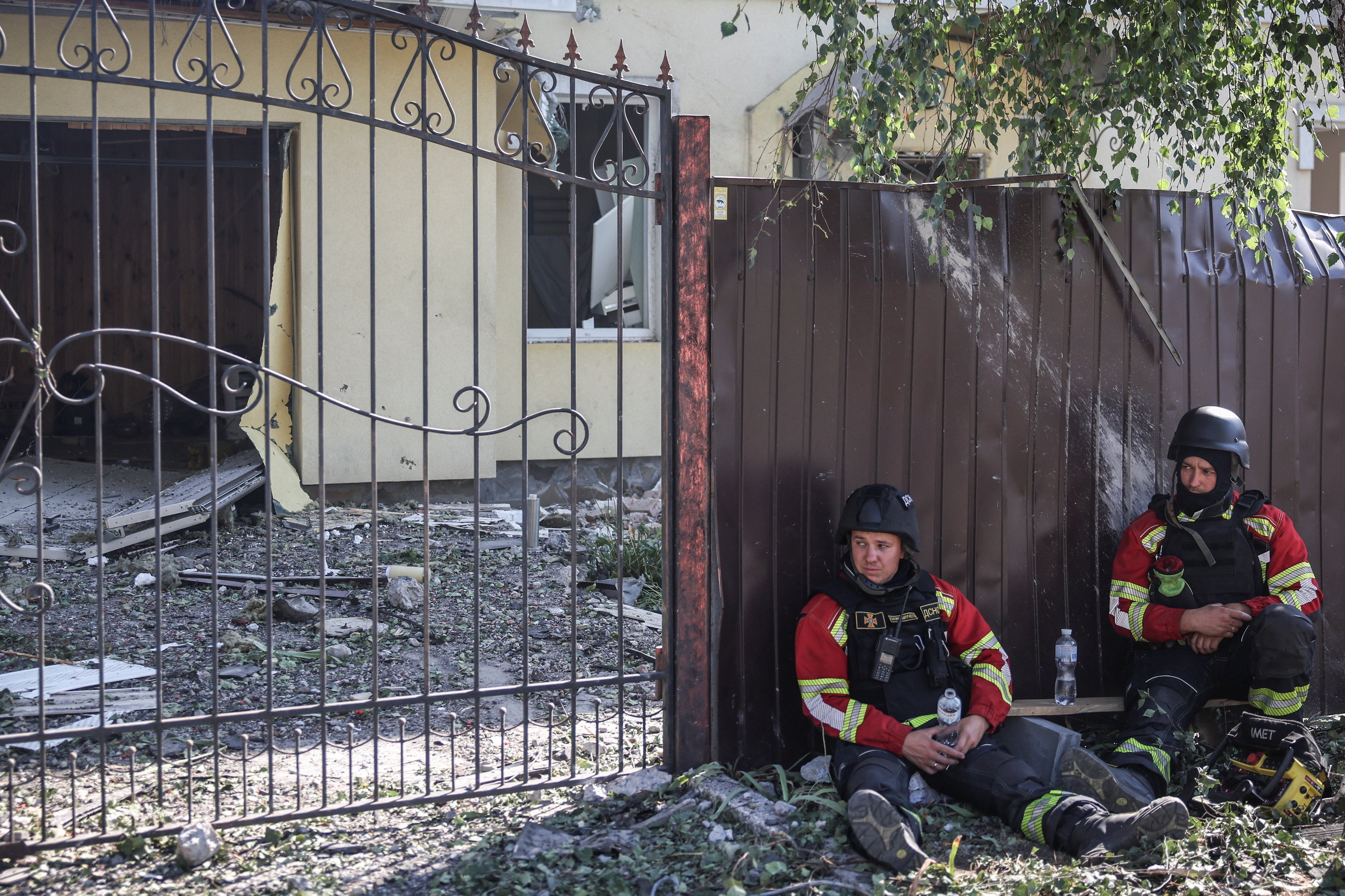 Rescuers look on near a damaged house at a site of a yesterday's Russian drone strike, amid Russia's attack on Ukraine, in the village of Myla, Kyiv region