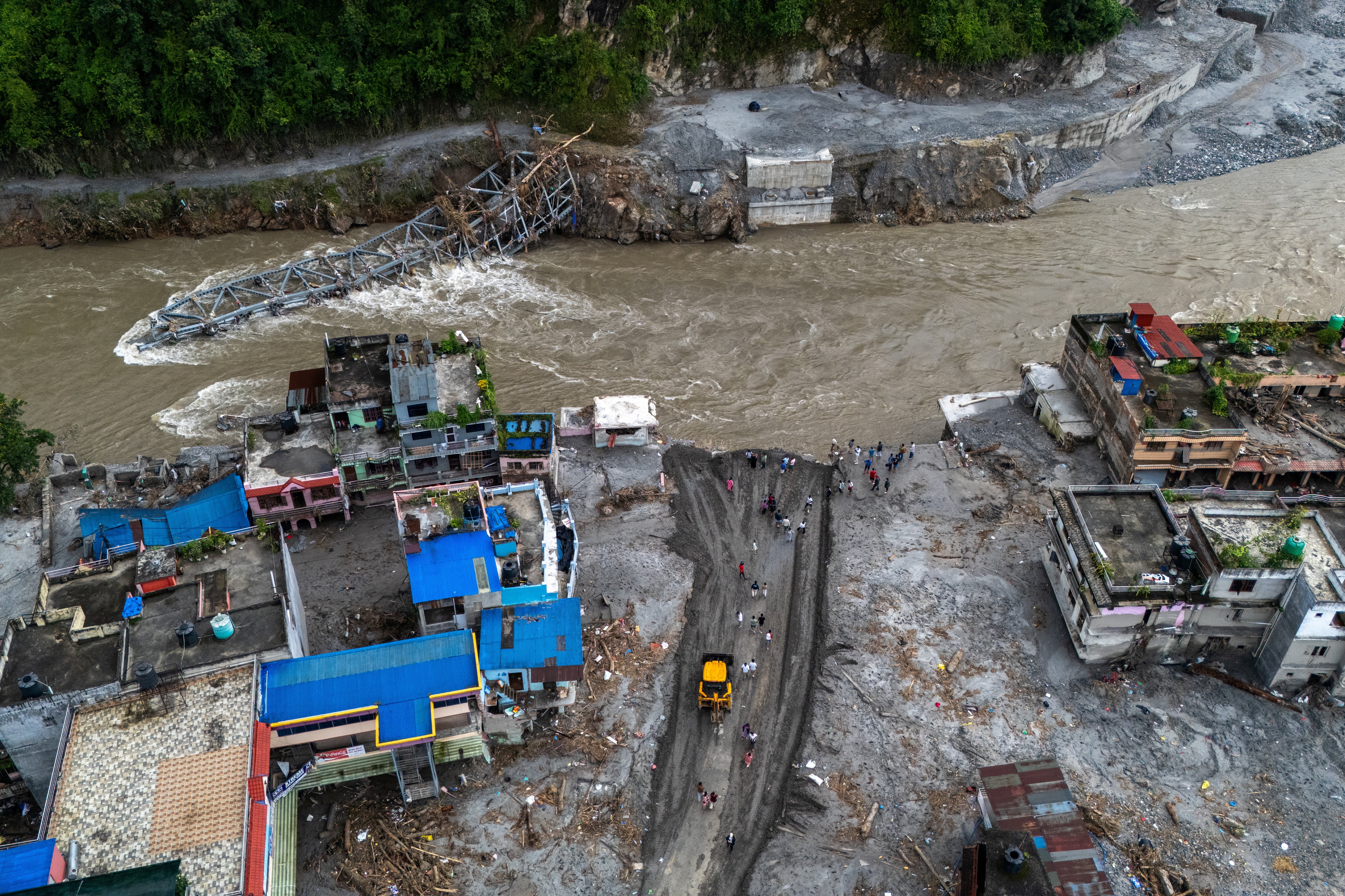 A drone view of houses in mud and the broken bridge after deadly flash floods and mudslide, at Devighat, Nuwakot district