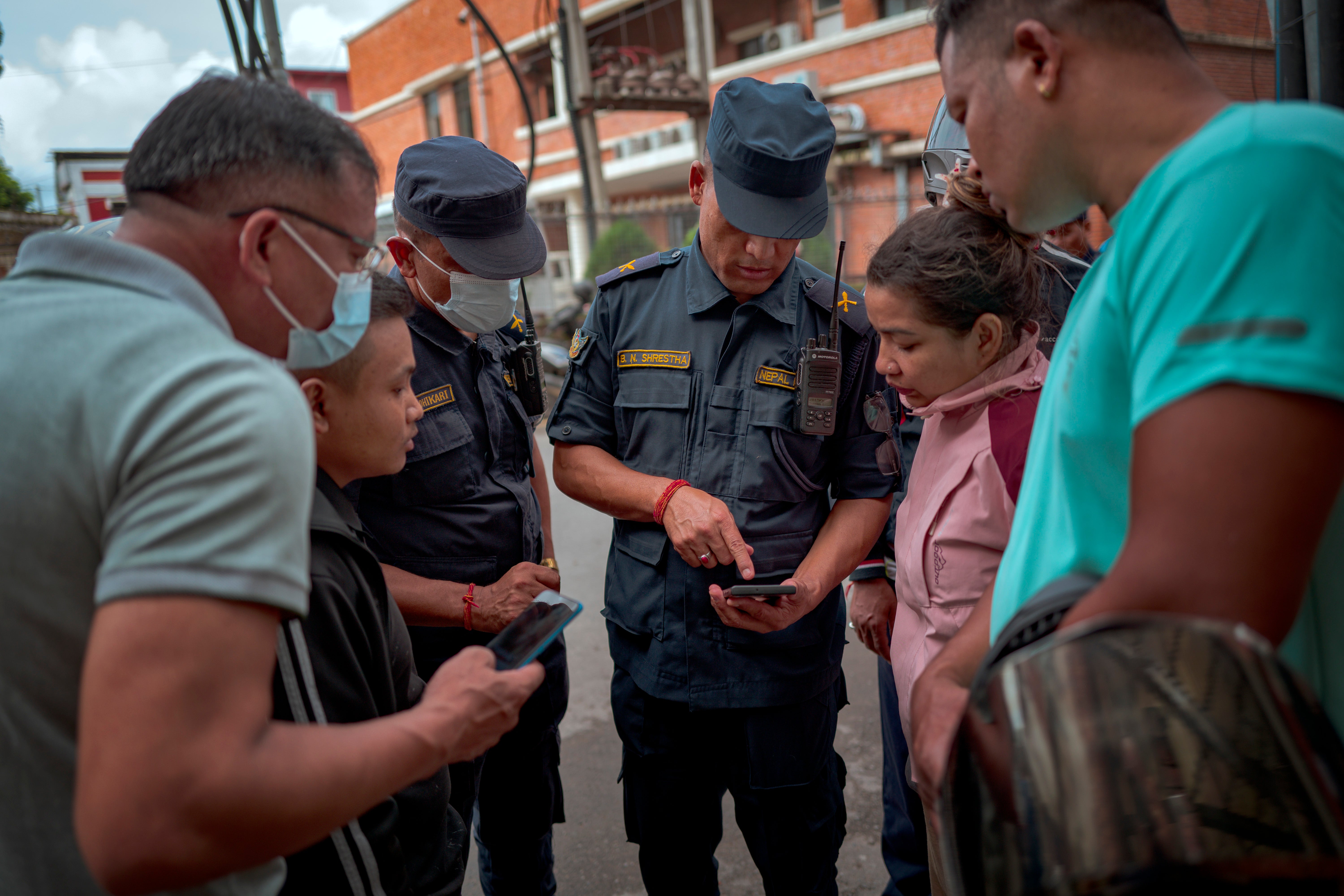 A woman inquires with police about her missing relative, outside Maharajgunj Medical Campus