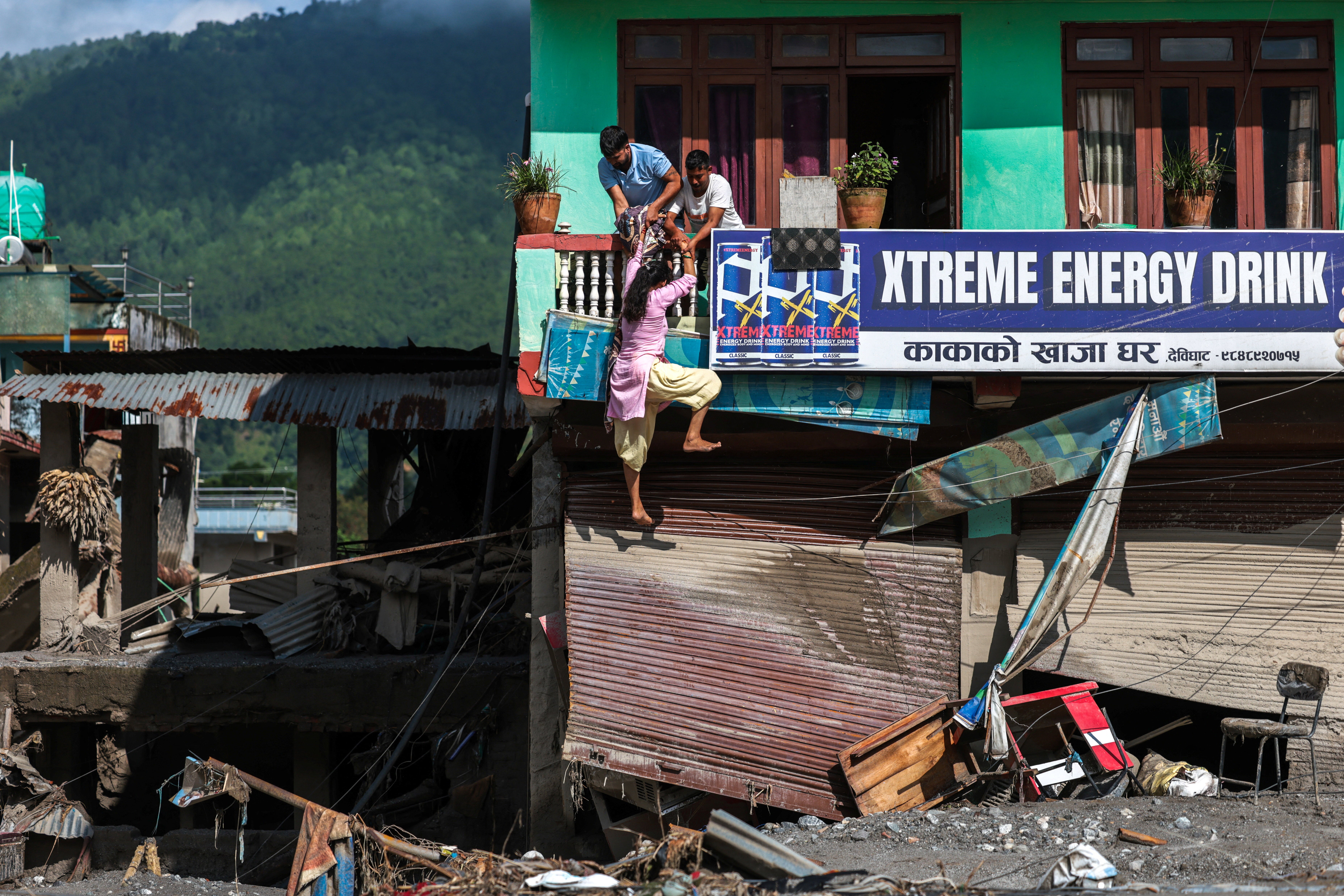 People try to enter their damaged house following deadly flash floods and mudslides, in Devighat, Nuwakot district, Nepal