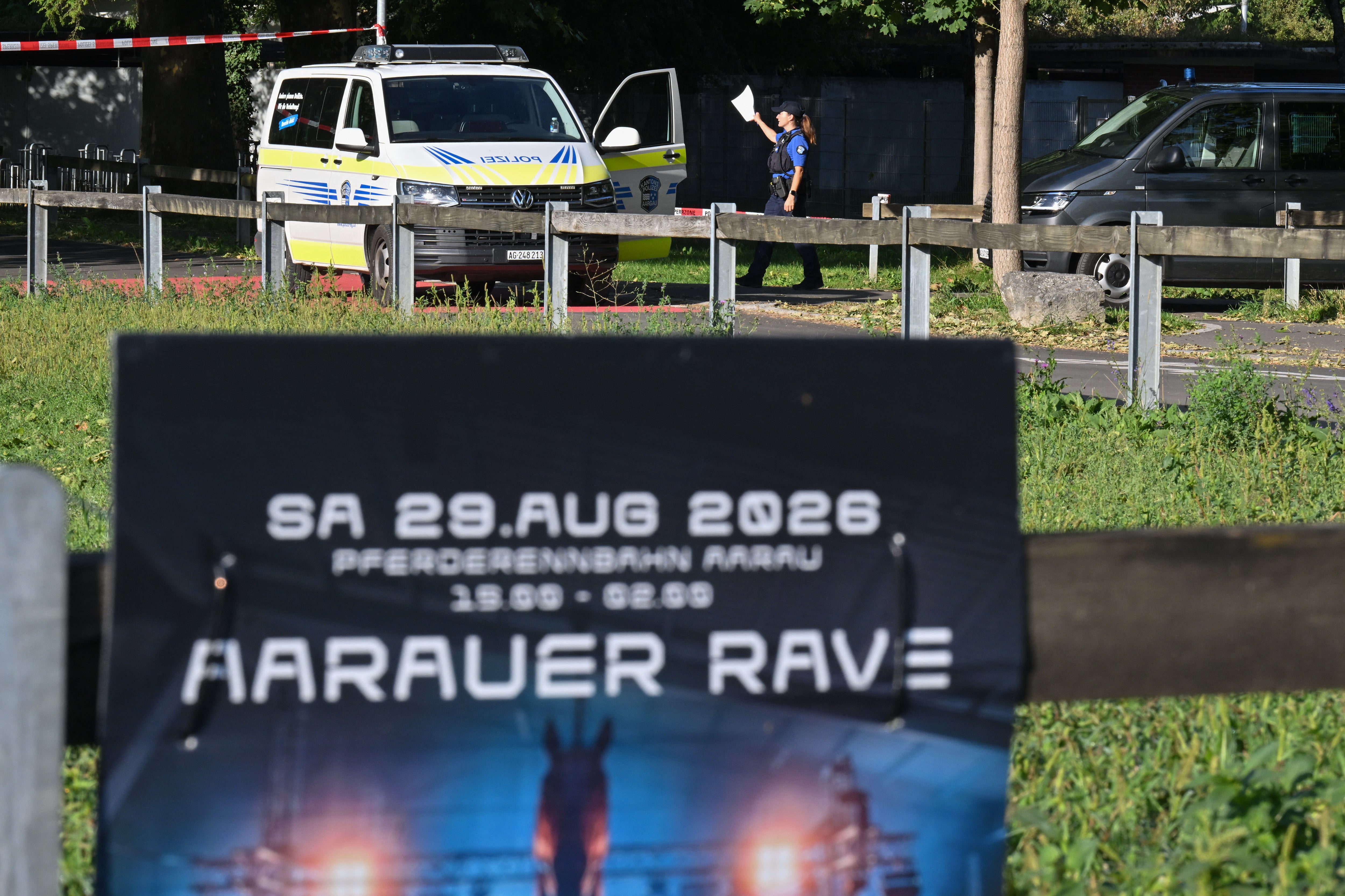 <p>Police officers secure the area behind a poster advertising a rave where a shooting occurred, in Aarau, northern</p>