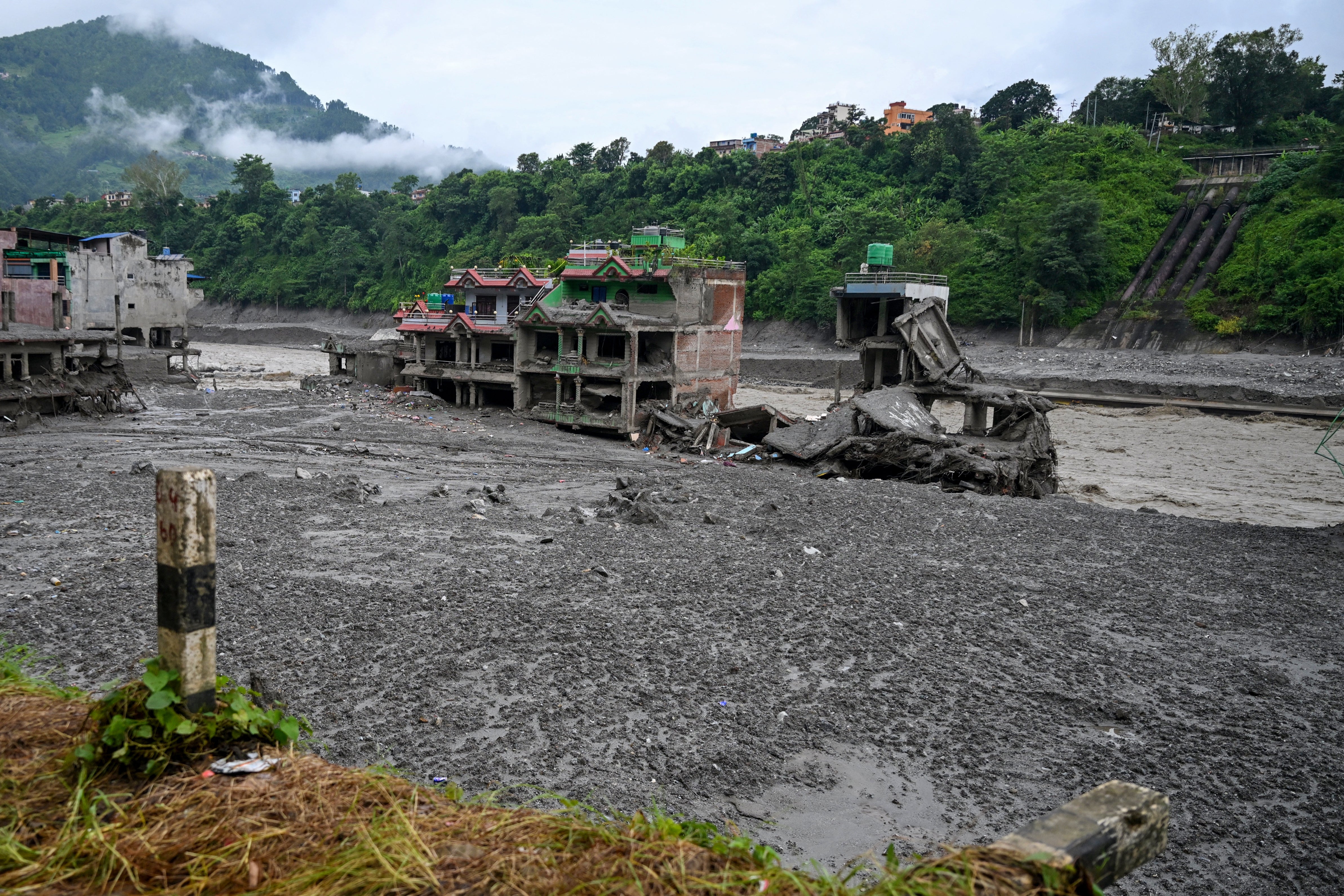 Damaged houses lie deluged in sludge after flash floods at Trishuli Center in Nepal's Nuwakot district on August 31, 2026. Nepal was buried on 31 August, with hundreds of bodies retrieved after a deadly, tsunami-like flood crashed through the Himalayan region, sweeping away villages and leaving thousands still missing. Distraught families have packed rescue stations and hospitals in search of their missing relatives, while others have faced the grim task of identifying bodies at overflowing morgues