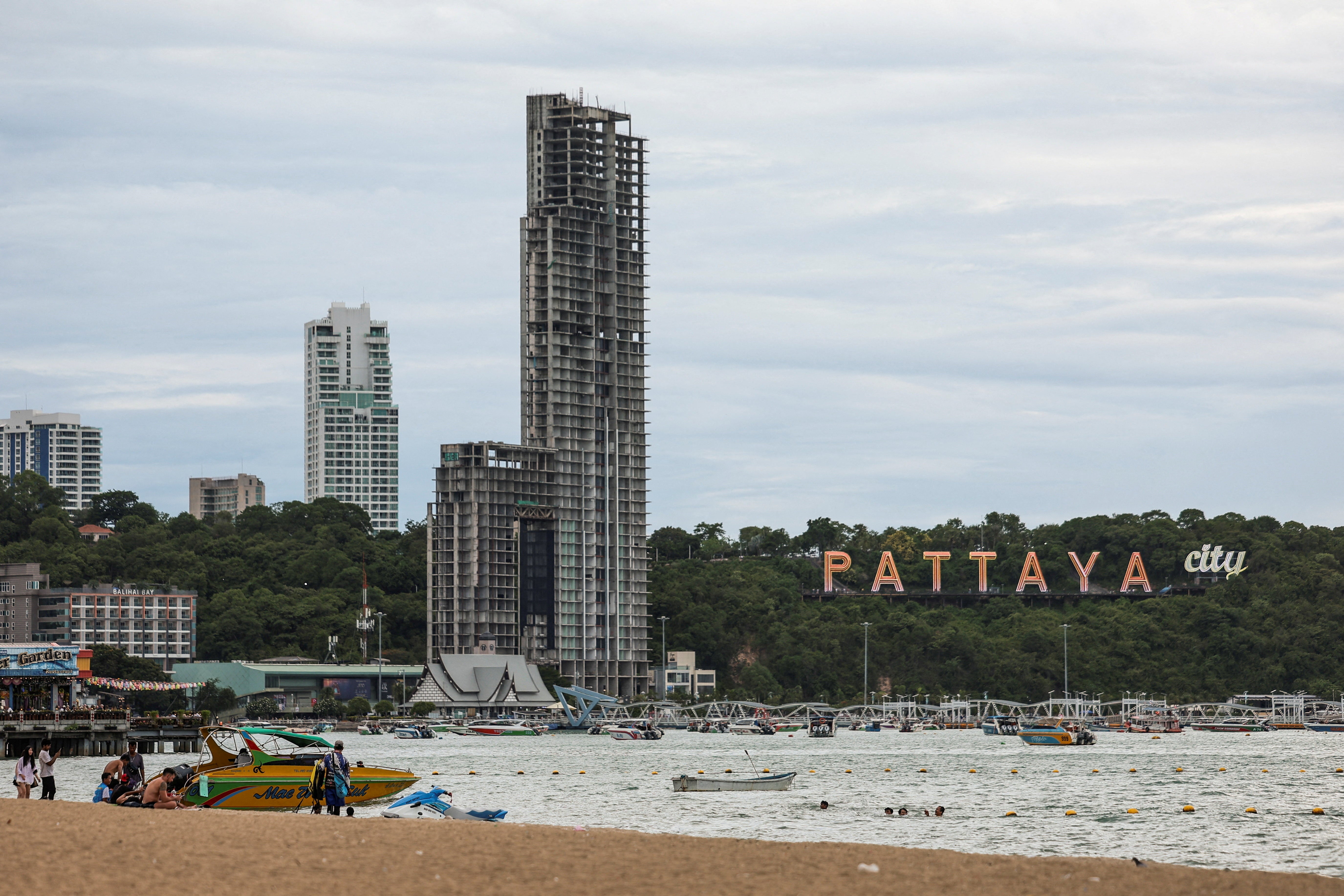 People relax at Pattaya Beach with the Pattaya City sign in the background in Pattaya City, Thailand, June 29, 2026