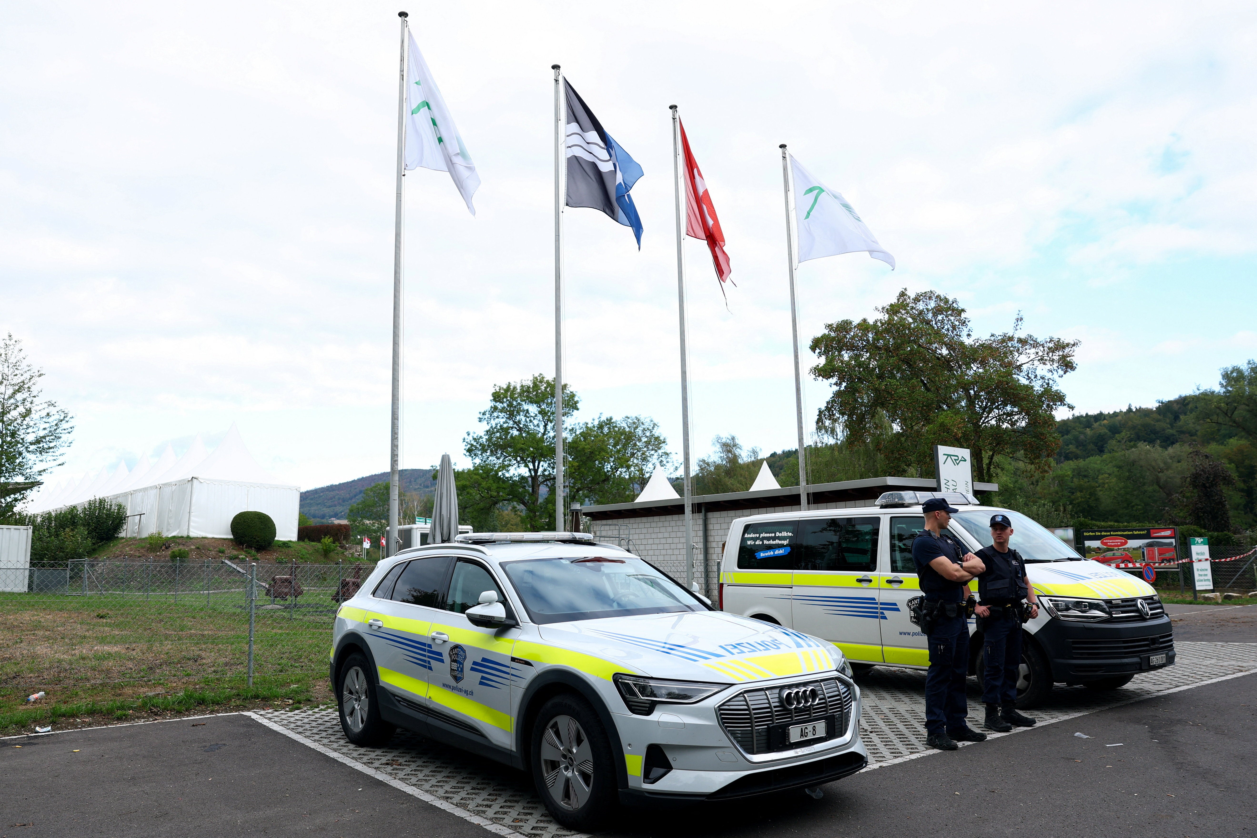 Police officers stand guard near the site of a rave party, following a deadly shooting incident at an event on Sunday, near the Schachen horse racing track, in Aarau