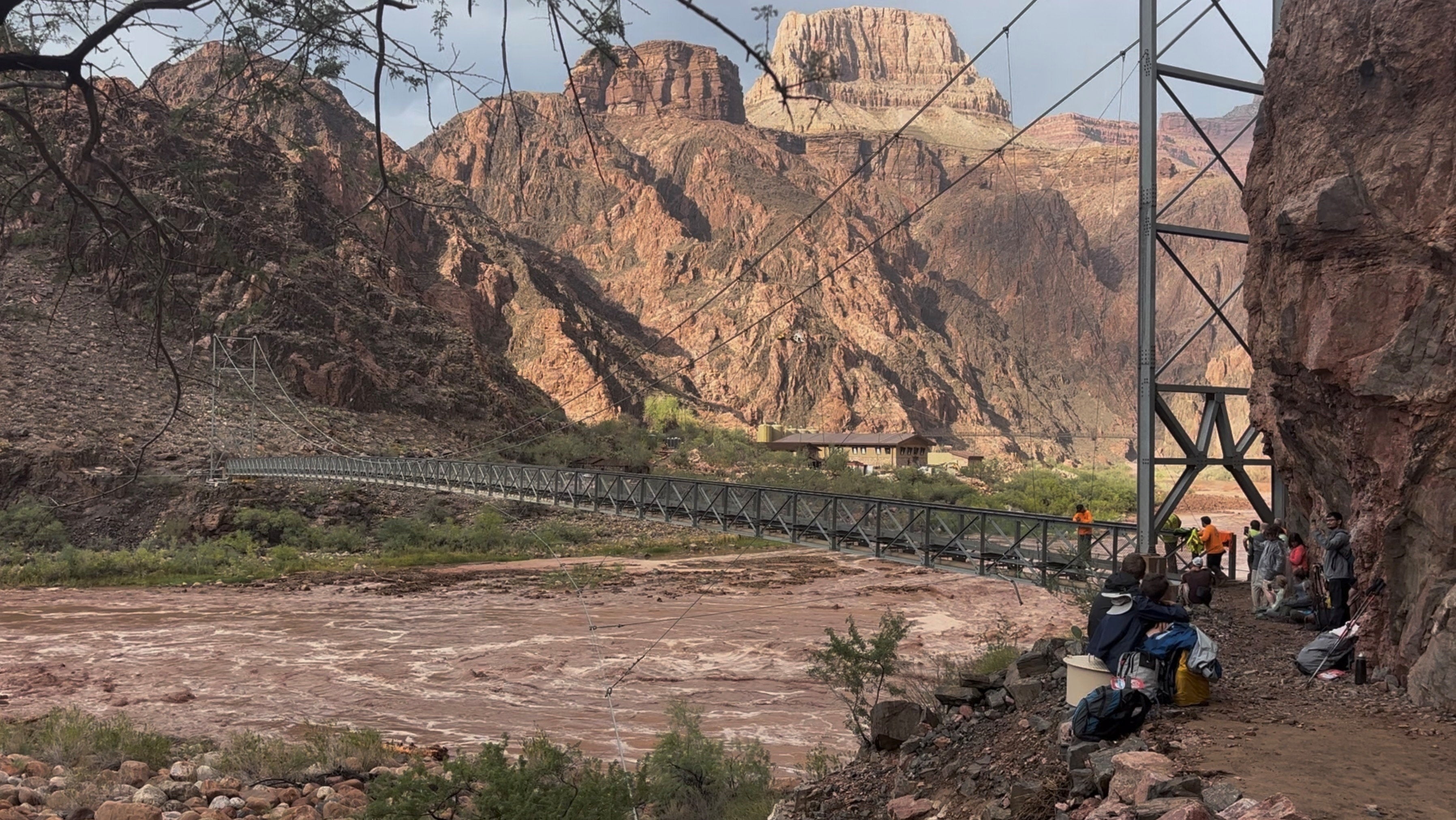 People wait near a bridge during flash flooding in Arizona’s Grand Canyon National Park Saturday afternoon. More than 60 park-goers were rescued