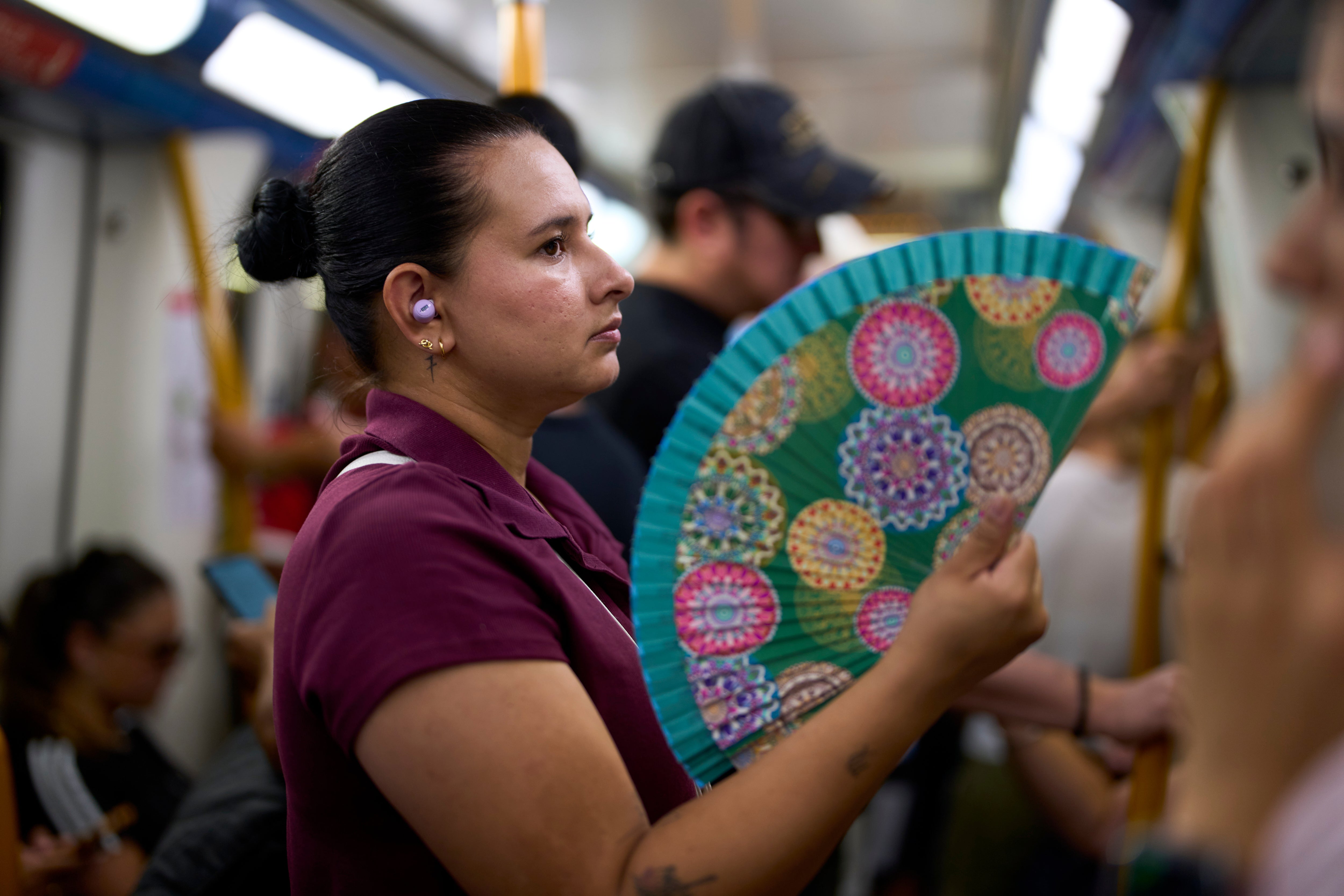 A woman uses a fan to cool herself on the subway in Madrid, Spain.