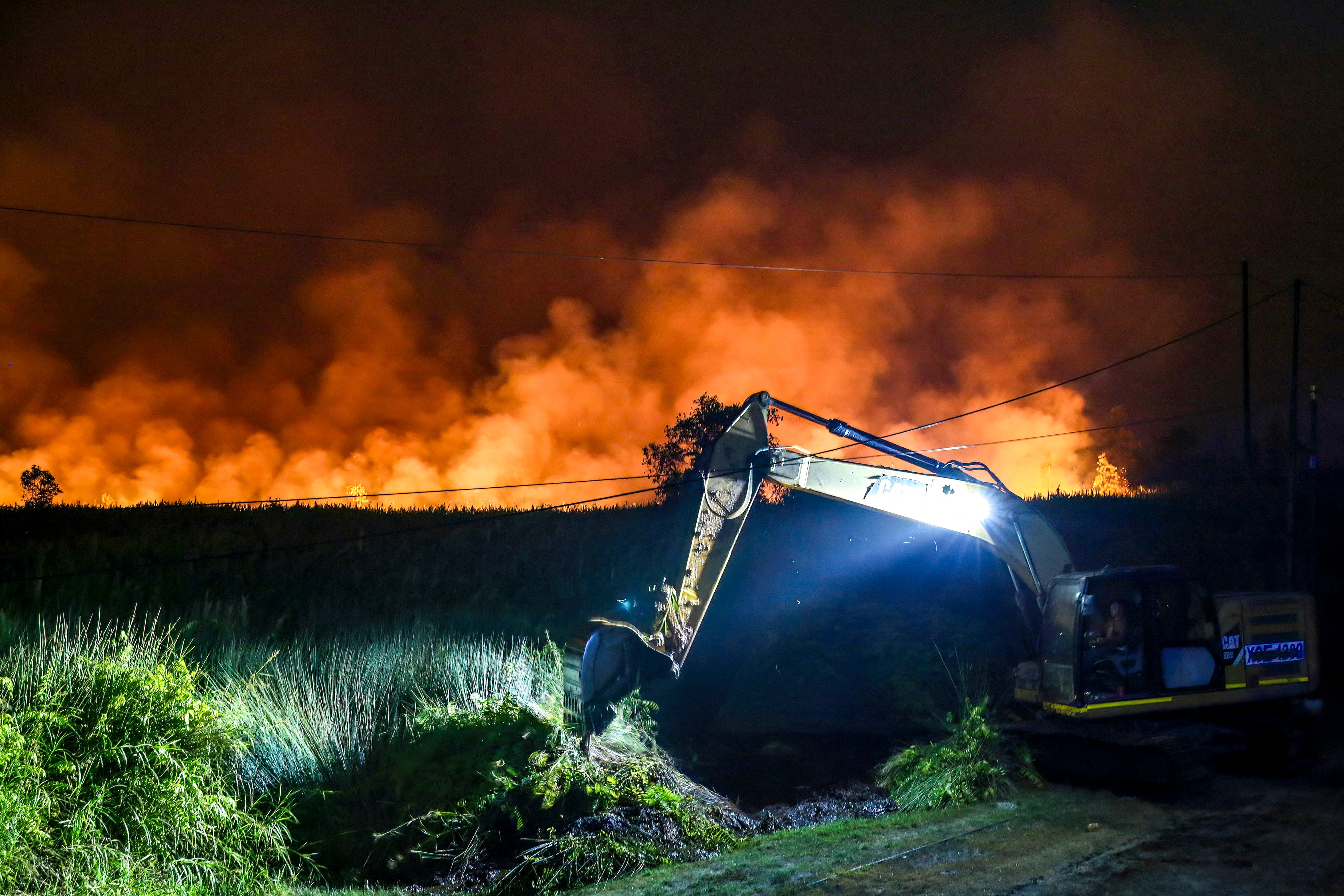 An excavator digs a trench in an attempt to extinguish a wildfire in the Tumbang Nusa area of Pulang Pisau