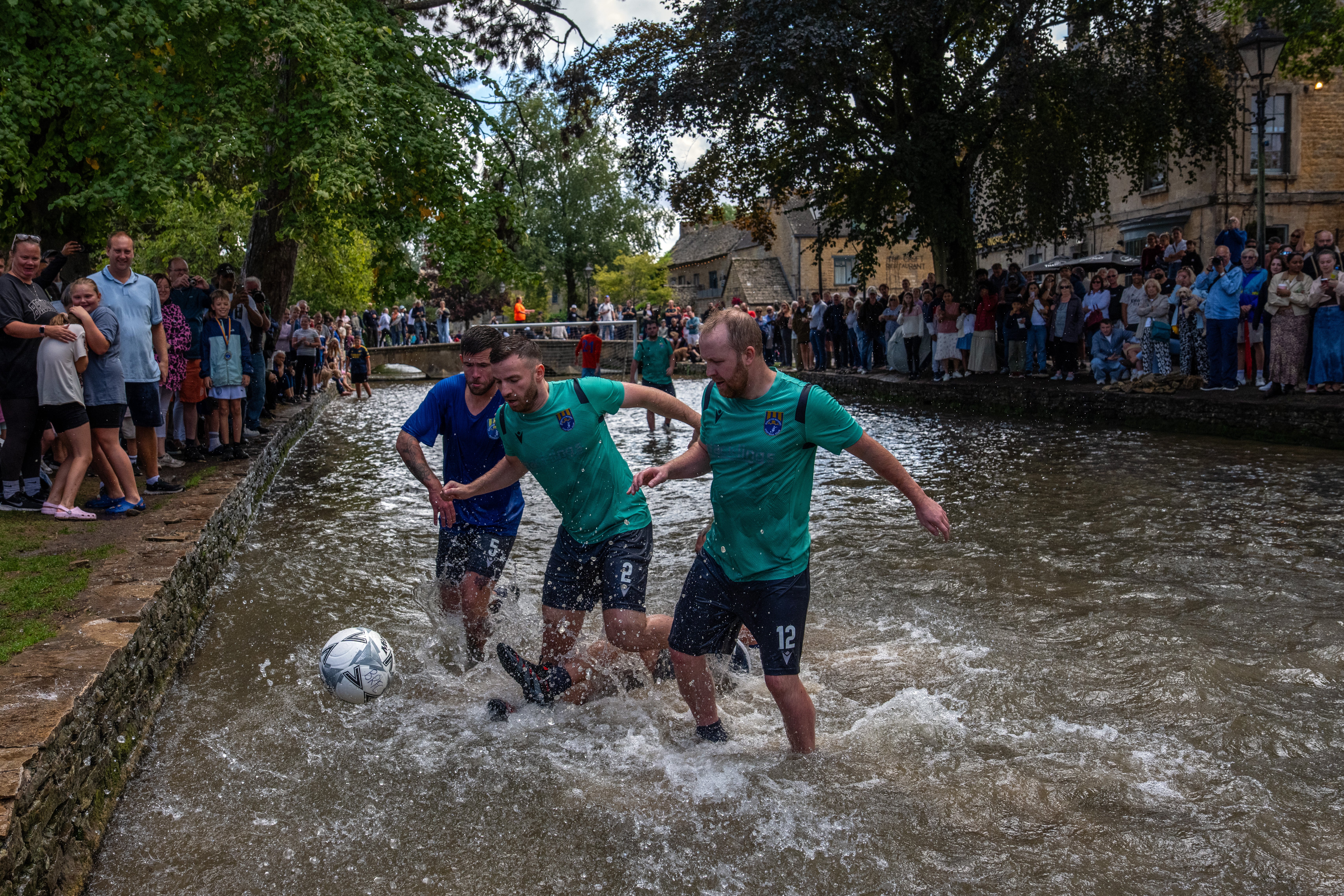 Players from Bourton Rovers First XI play against Bourton Rovers Second XI during the annual Bourton-on-the-Water Football Match played on the River Windrush