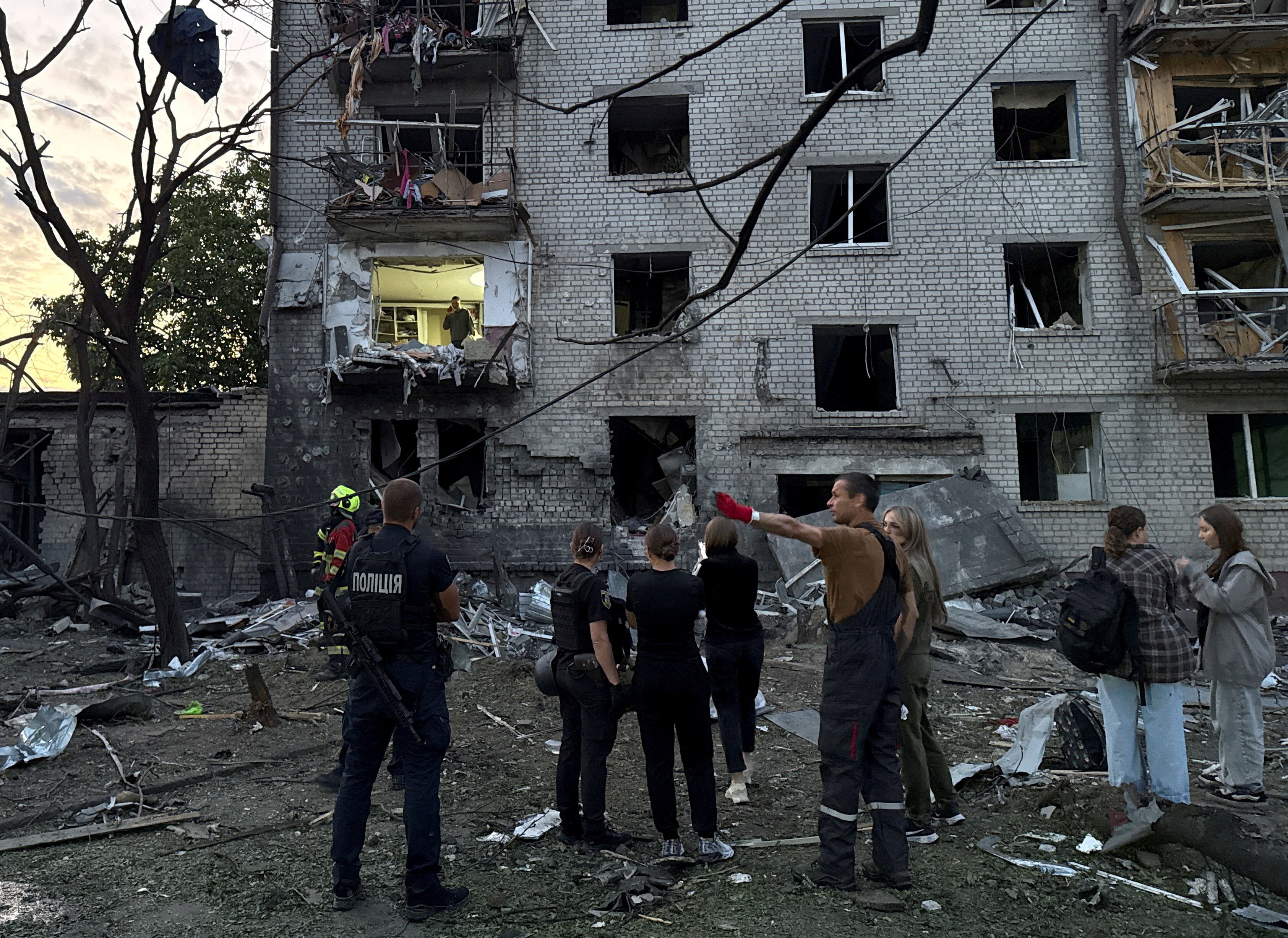 Police officers and residents stand at a site of an apartment building hit by a Russian missile (Reuters)