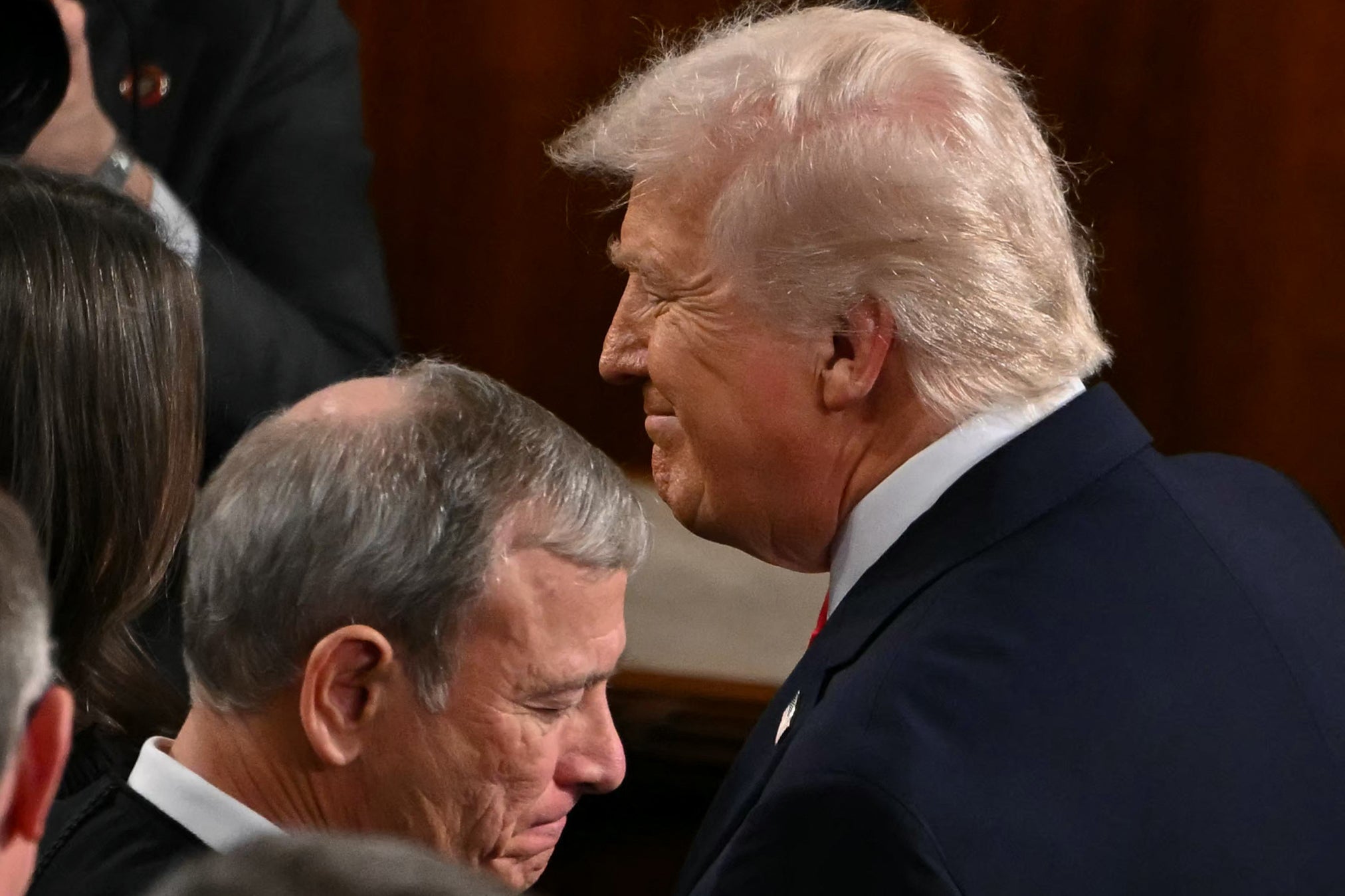 Trump walks by Supreme Court Chief Justice John Roberts as he arrives to deliver his State of the Union address in the House Chamber of the US Capitol