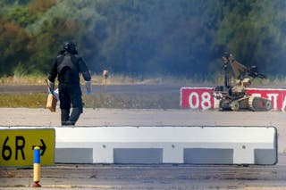 File photo: A police officer in protective clothing walks next to an explosive-disarming robot (EOD) at Leipzig/Halle Airport in Schkeuditz, Germany
