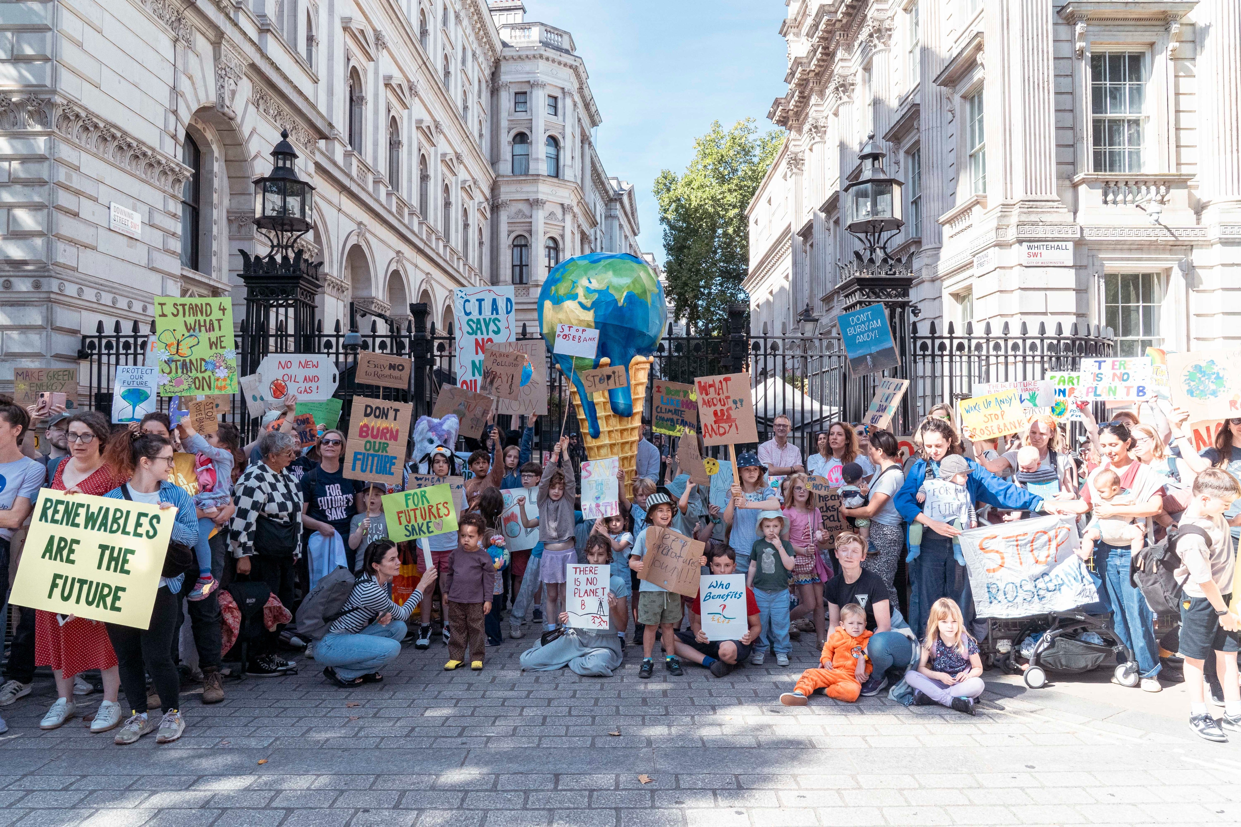Mothers and children with Mothers Rise Up gather outside 10 Downing Street with a giant melting-planet ice cream, calling for urgent action to protect children from extreme heat
