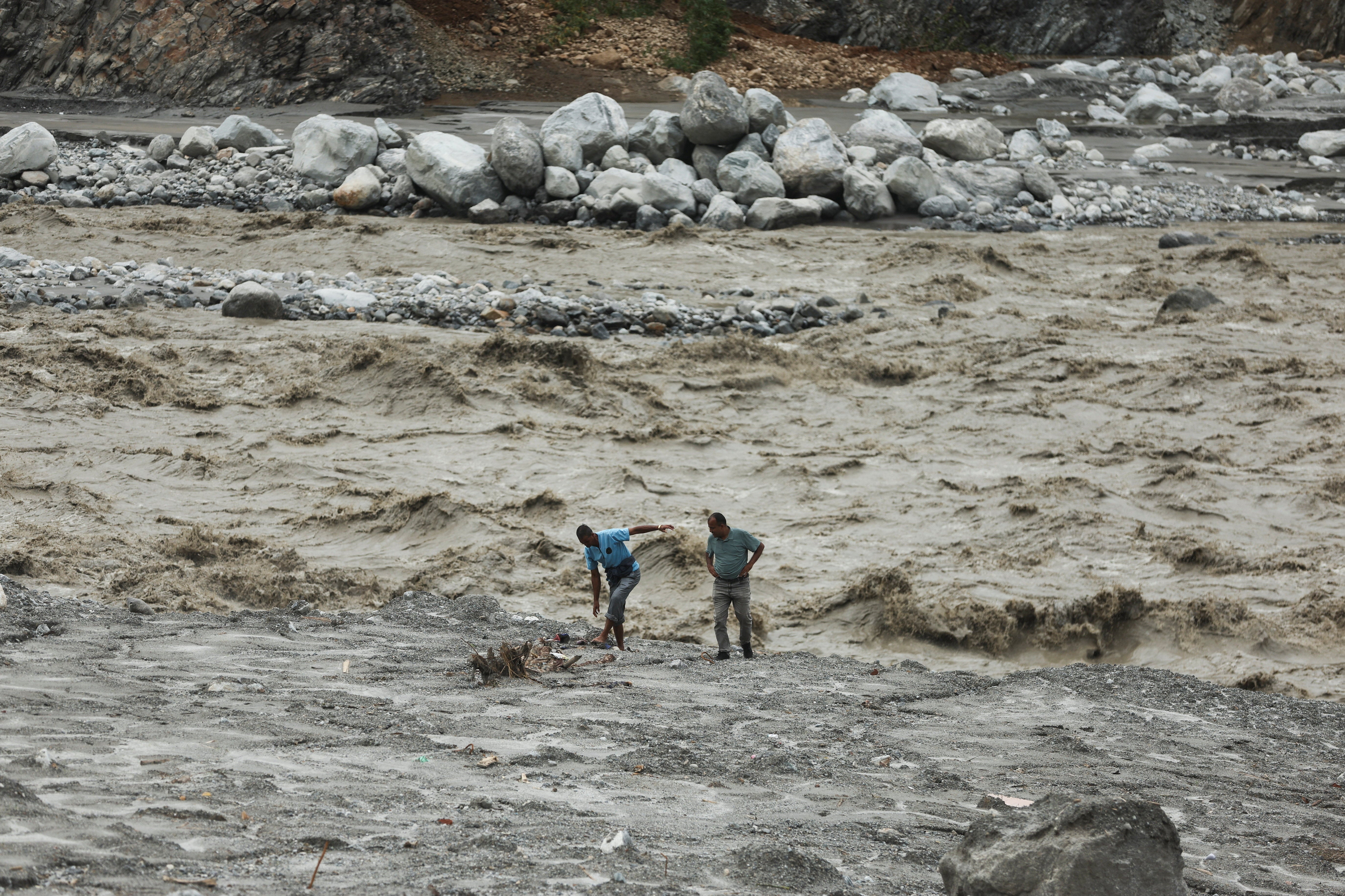 People walk by the banks of the Trishuli river after mudslides (Reuters)