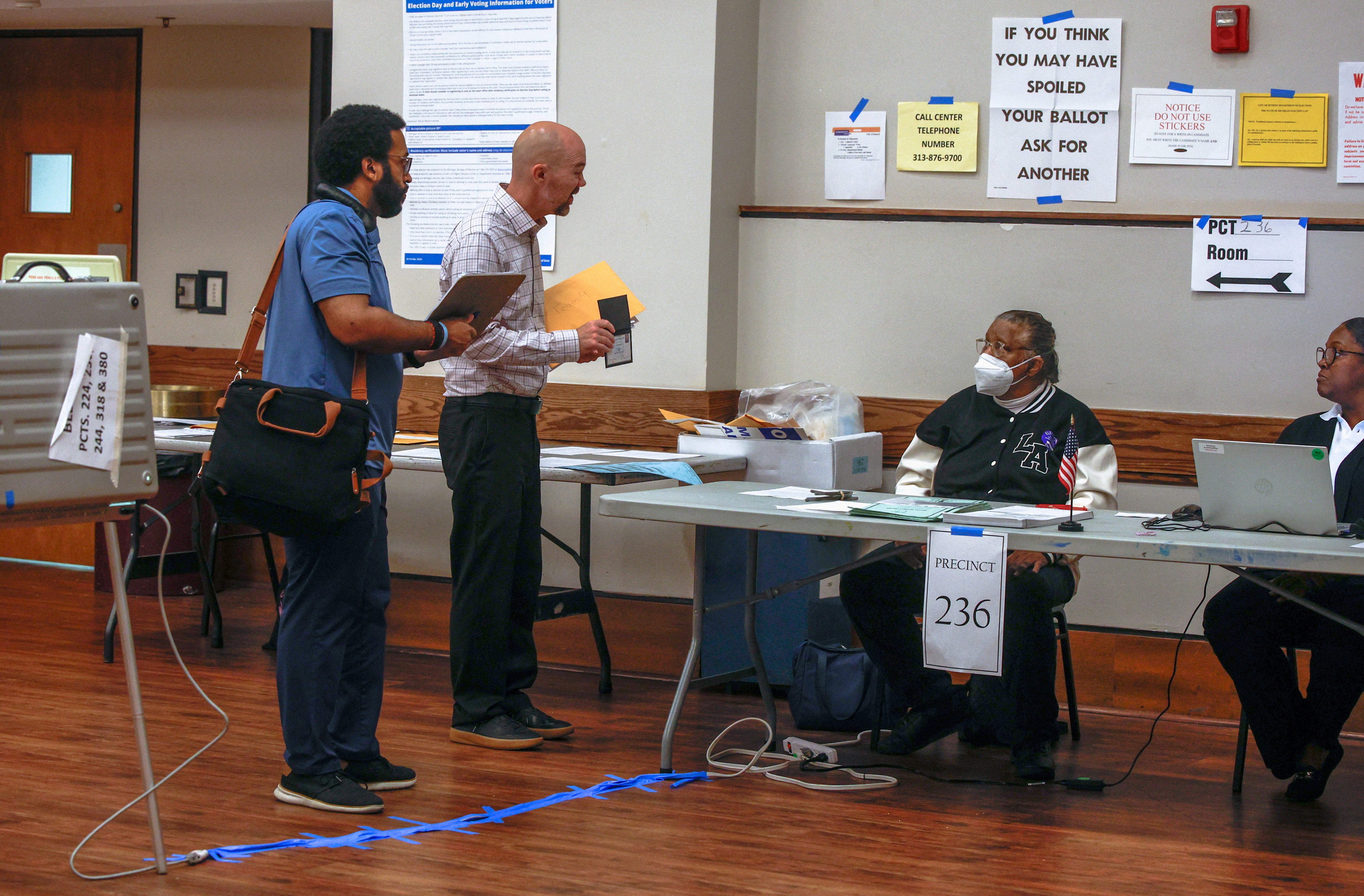 A poll monitor from the Department of Justice, seen flashing a badge to election workers in Detroit, is among hundreds of DOJ observers being deployed to polling locations this year