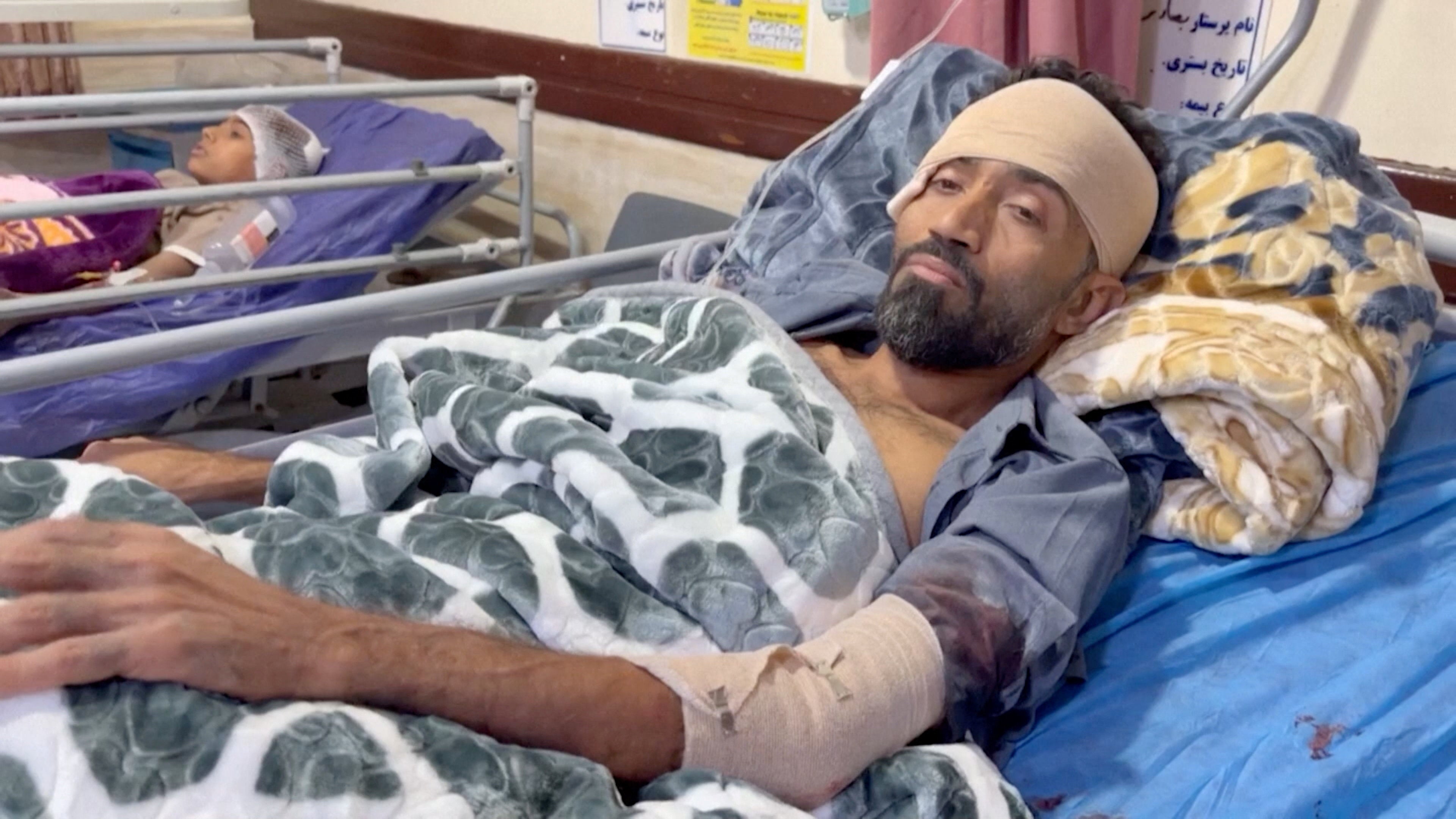 An injured victim lies in a hospital bed following an attack at a wedding near Sirik