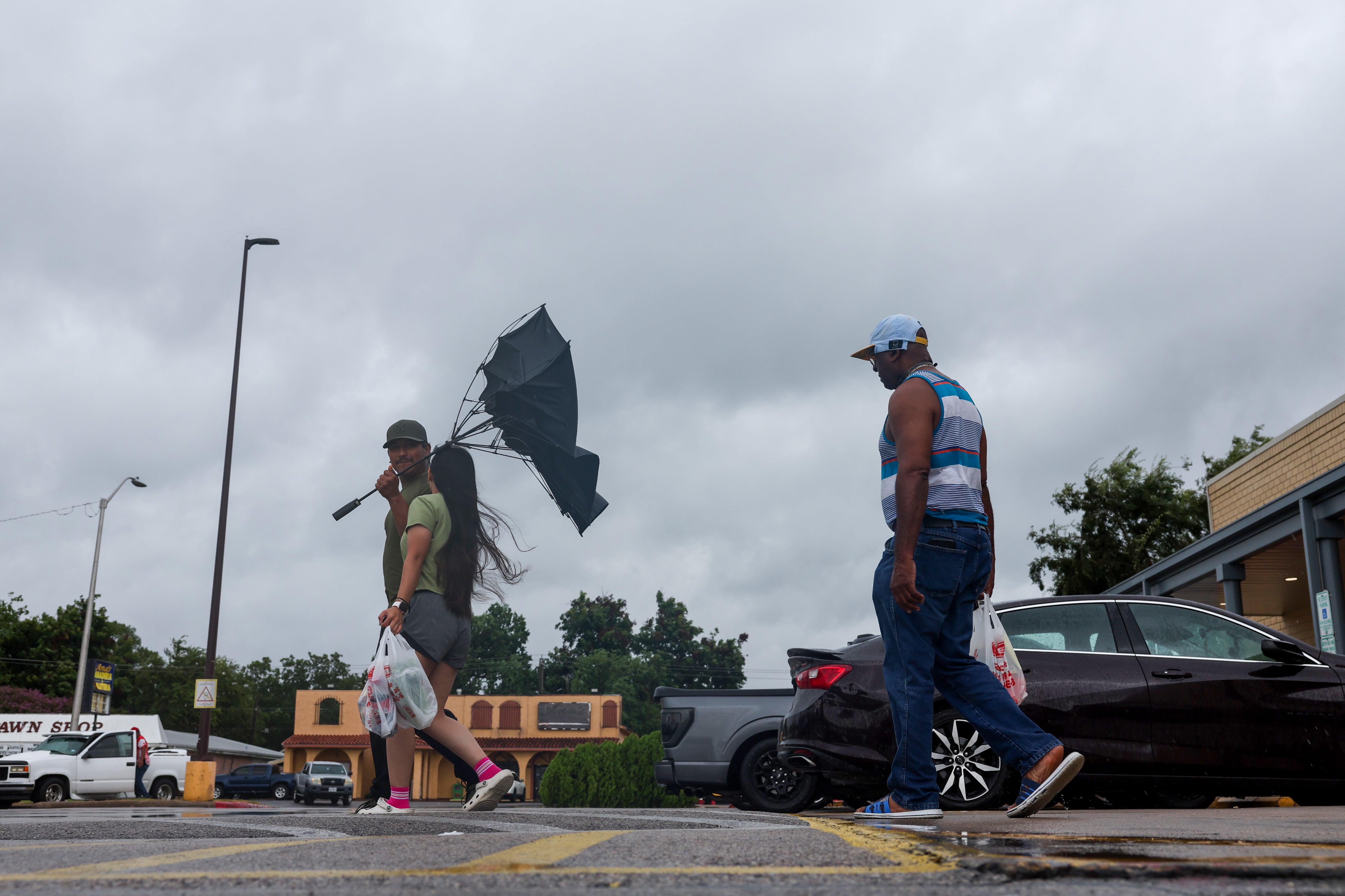 A man tries to hold onto an umbrella as he walks out of a grocery storm on Tuesday in Port Arthur, Texas. Edouard made landfall along the Texas-Louisiana border on Tuesday afternoon