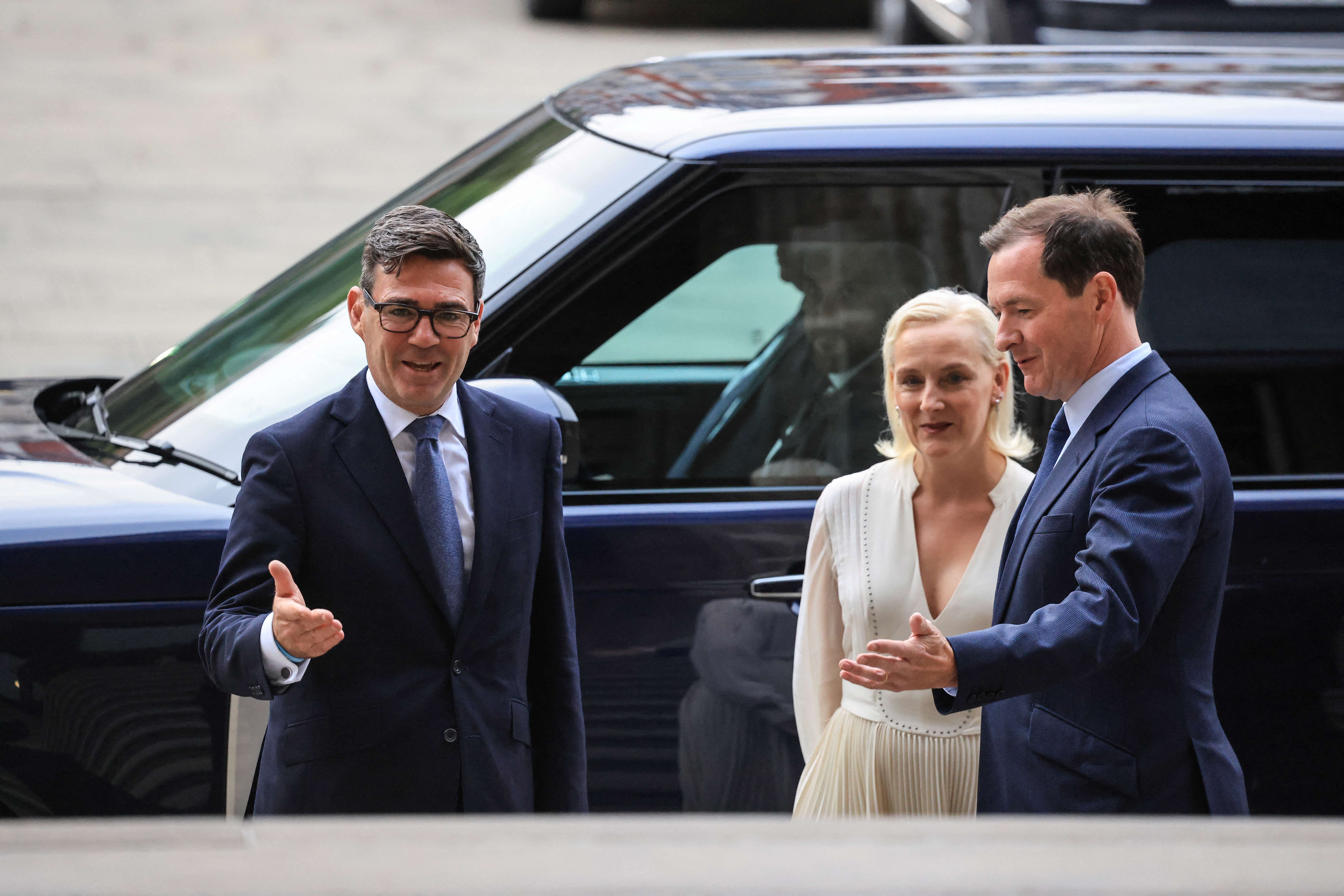 Andy Burnham (L) and his wife Marie-France van Heel (centre) are greeted by British Museum chair George Osborne (R)