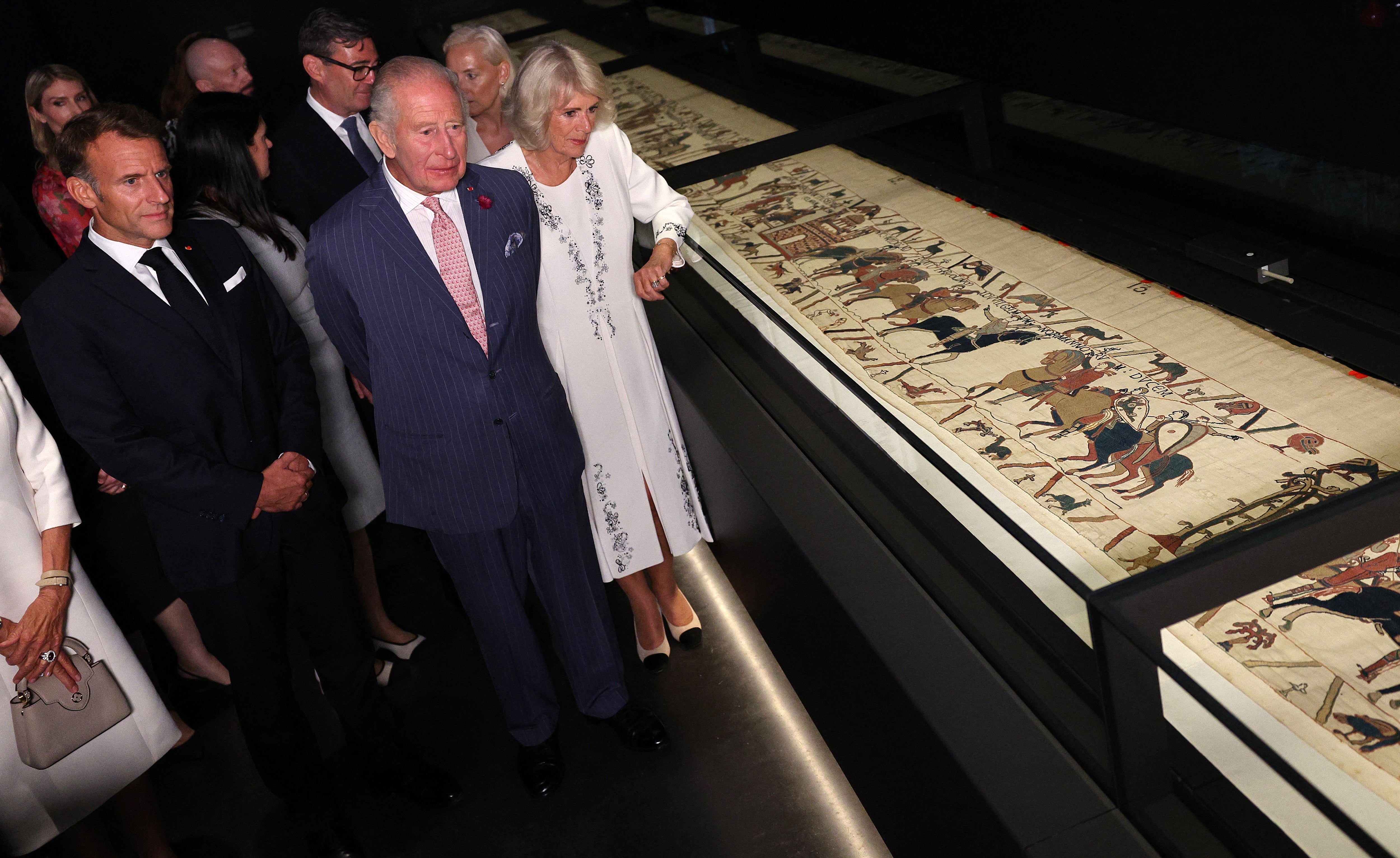 King Charles III and Queen Camilla alongside Emmanuel Macron view a section of the Bayeux Tapestry