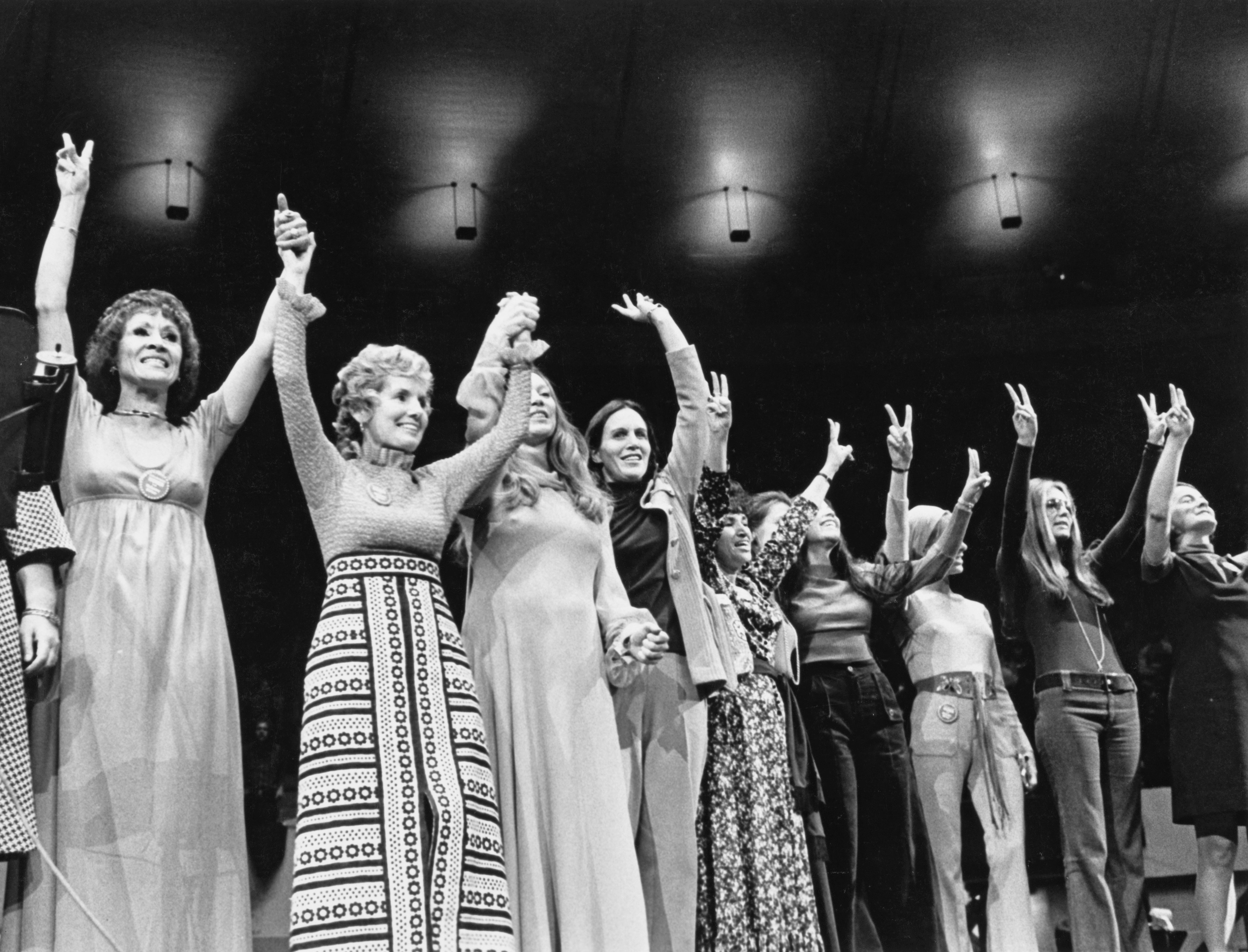 Eleanor McGovern (1921-2007; second left), wife of US Democratic politician George McGovern, alongside US actress Shirley MacLaine (third left), and US journalist and writer Gloria Steinem (second right) raise their arms at the 'curtain call' of the 'Women for McGovern campaign rally, held at Madison Square Garden in New York City, New York, 27th October 197