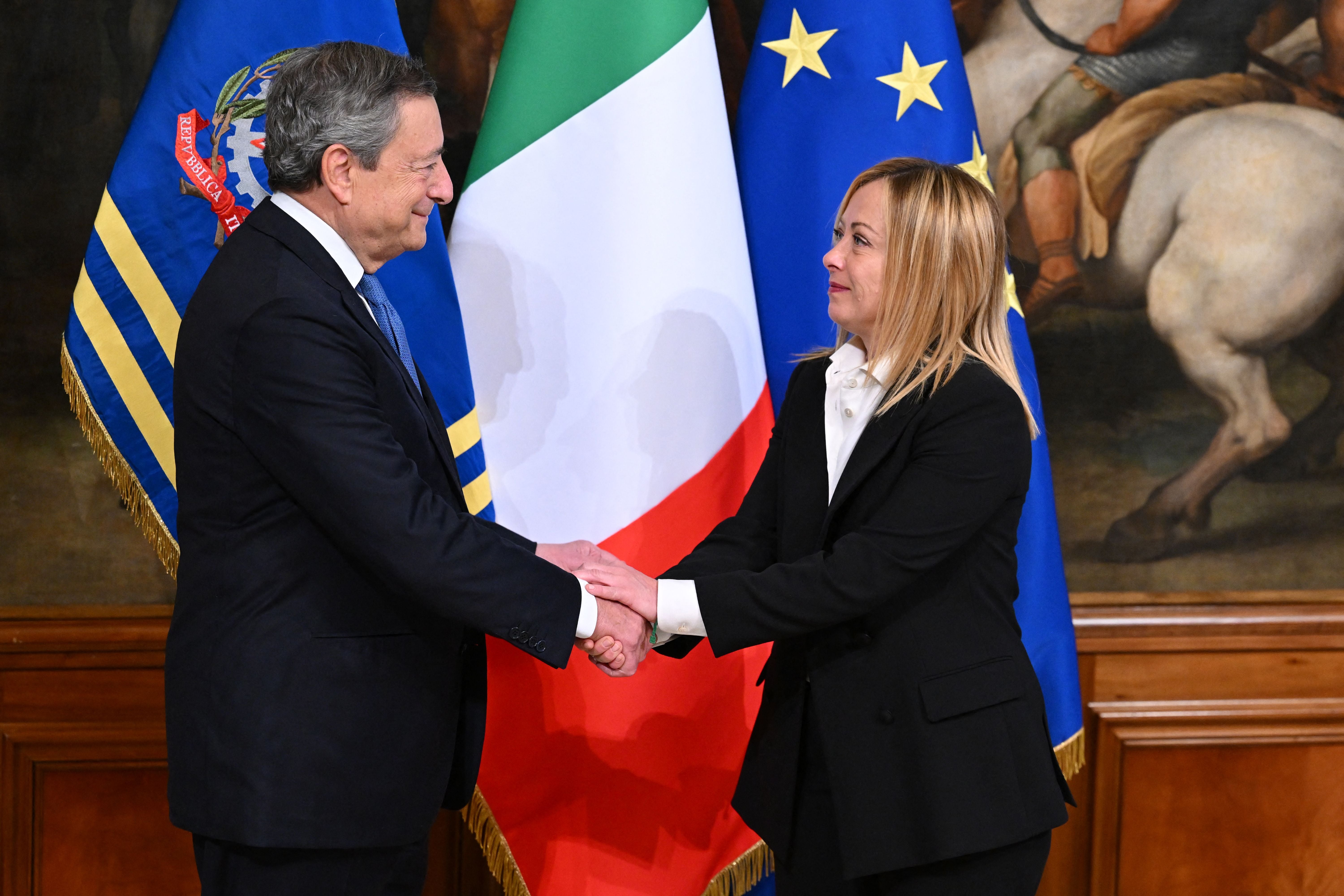 Italy's outgoing prime minister, Mario Draghi and Italy's new prime minister, Giorgia Meloni shake hands during the cabinet minister bell handover ceremony at Palazzo Chigi in Rome on October 23, 2022