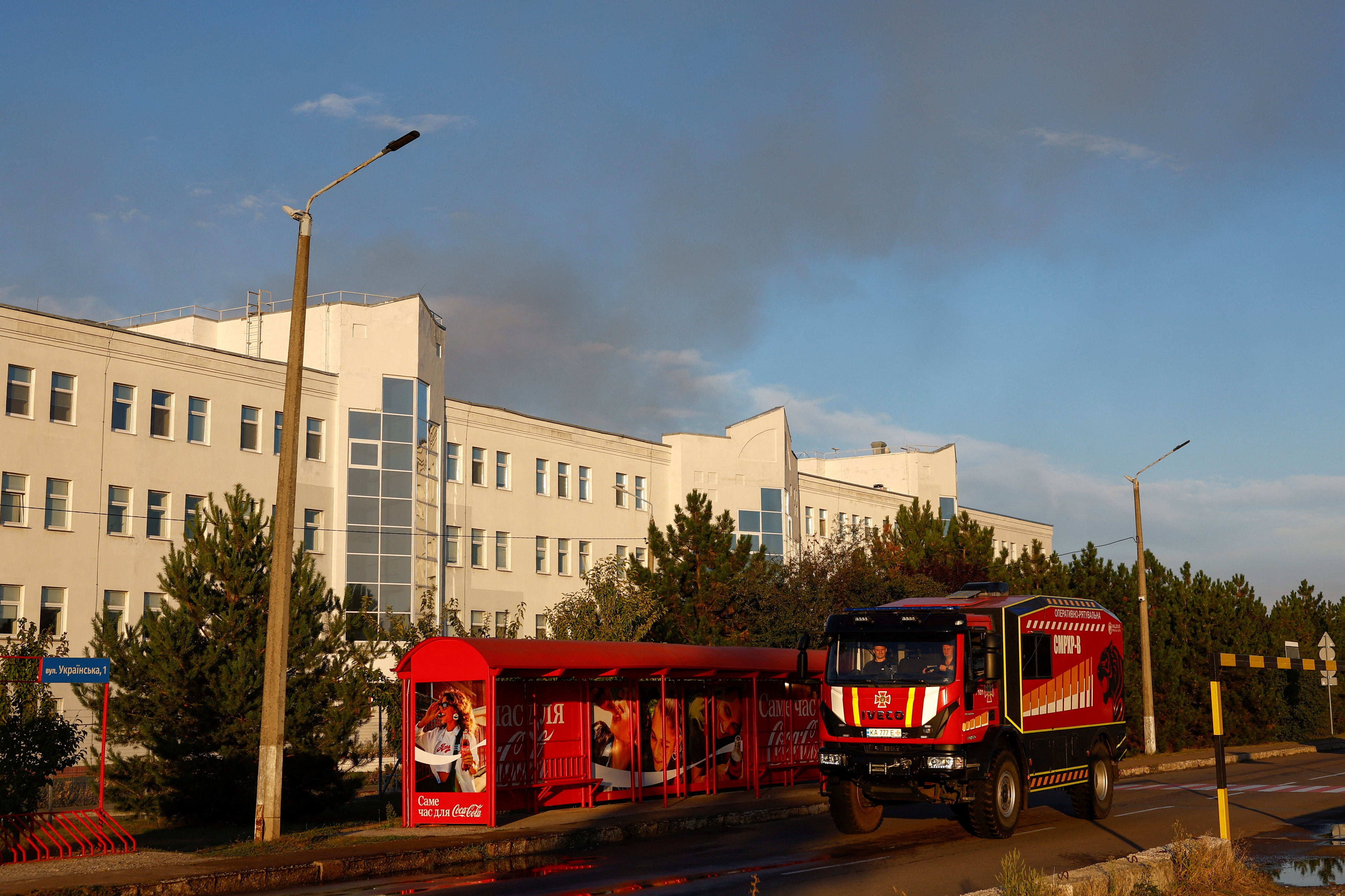 Firefighters drive along a road while smoke rises over a Coca-Cola factory after it was hit by a Russian drone strike, amid Russia's attack on Ukraine, in Kyiv Region, Ukraine September 3, 2026. (Reuters)