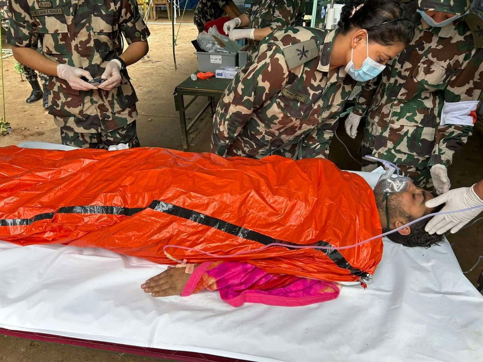 A survivor who was among two people rescued after being trapped inside a tunnel at the Trishuli-3A Hydropower Project following devastating floods and mudslides, receives medical attention (Reuters)