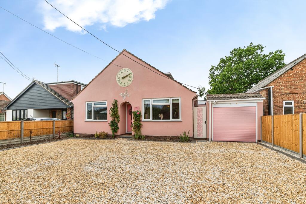 The front of the chalet style house is painted pink, including the garage and front door