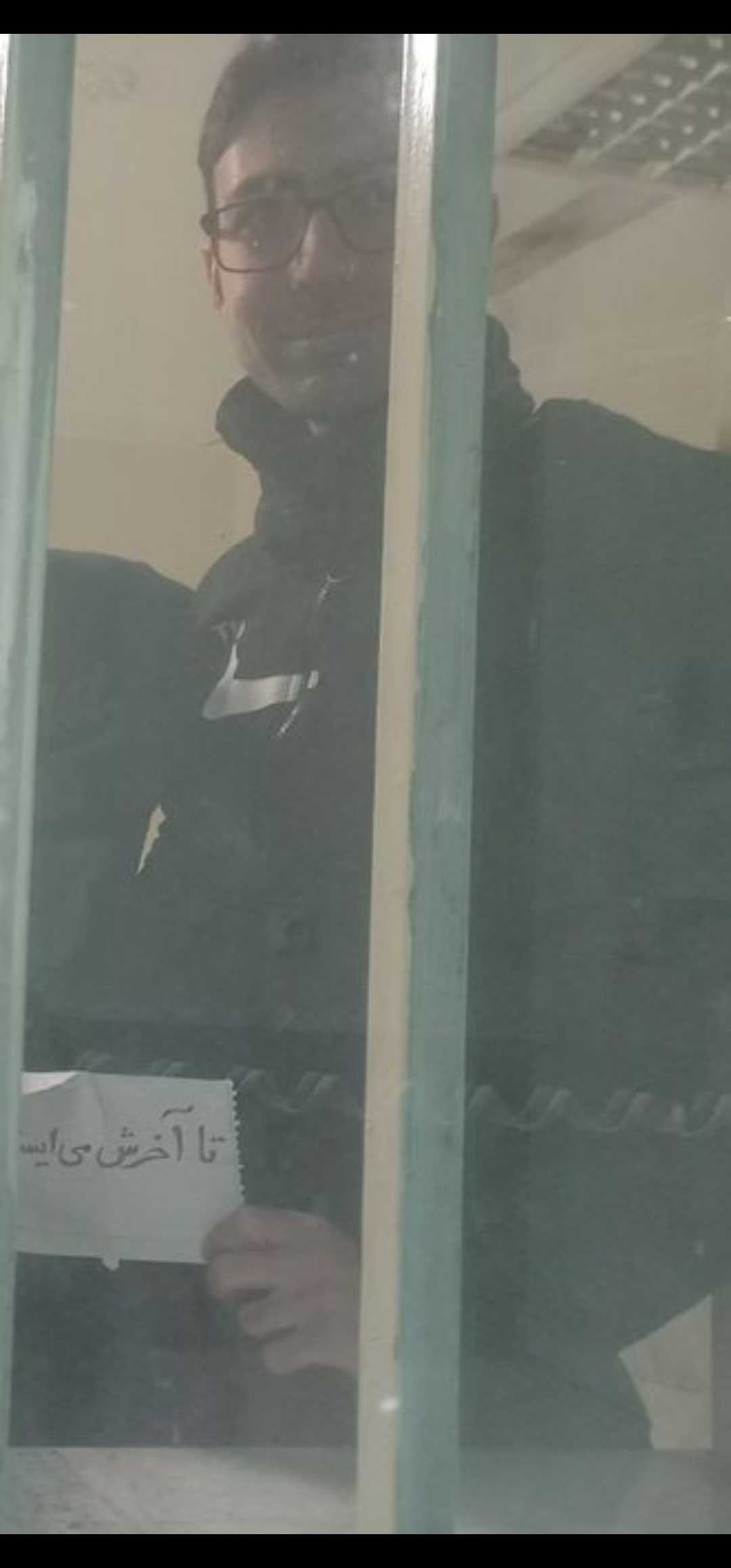 In this image, which is believed not to have been previously published, executed political prisoner and PMOI member Vahid Baniamerian holds a note reading: 'We stand until the end. January 2026. Evin Prison'