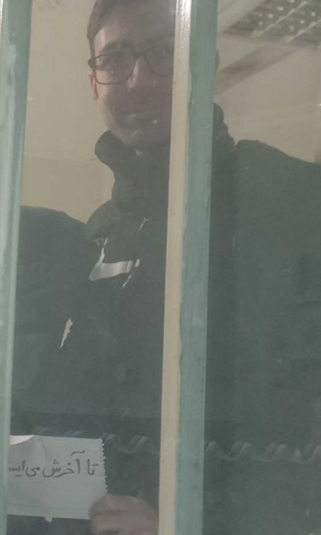 In this image, which is believed not to have been previously published, executed political prisoner and PMOI member Vahid Baniamerian holds a note reading: 'We stand until the end. January 2026. Evin Prison' (Handout)