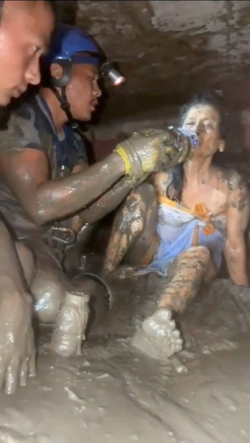 Rescuers give water to a woman as she is rescued from a house, following deadly flash floods and a mudslide, at a location given as Nuwakot, Nepal