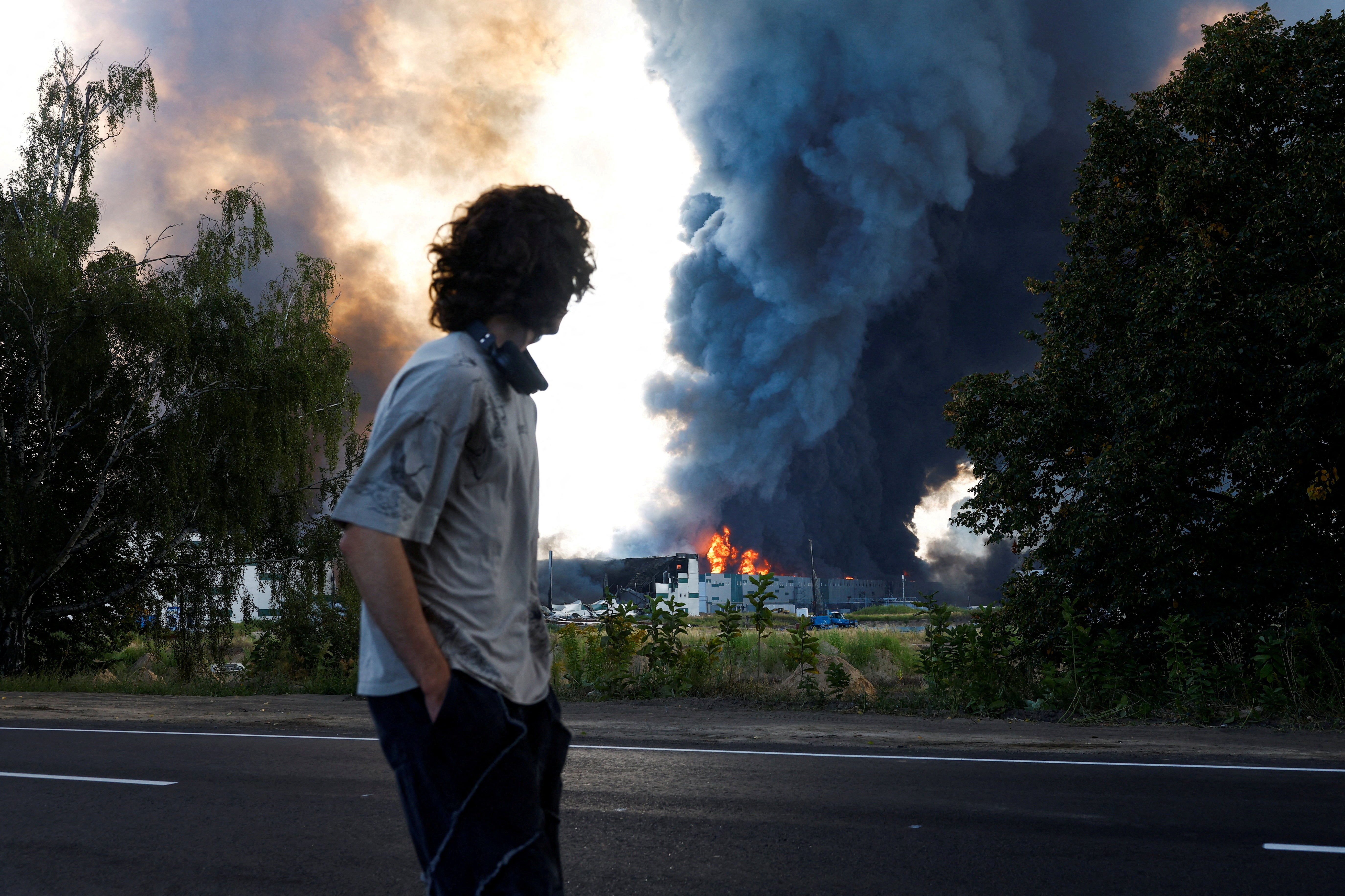 A man looks on as smoke rises over a warehouse, which was hit by a Russian drone strike, in Kyiv region (Reuters)