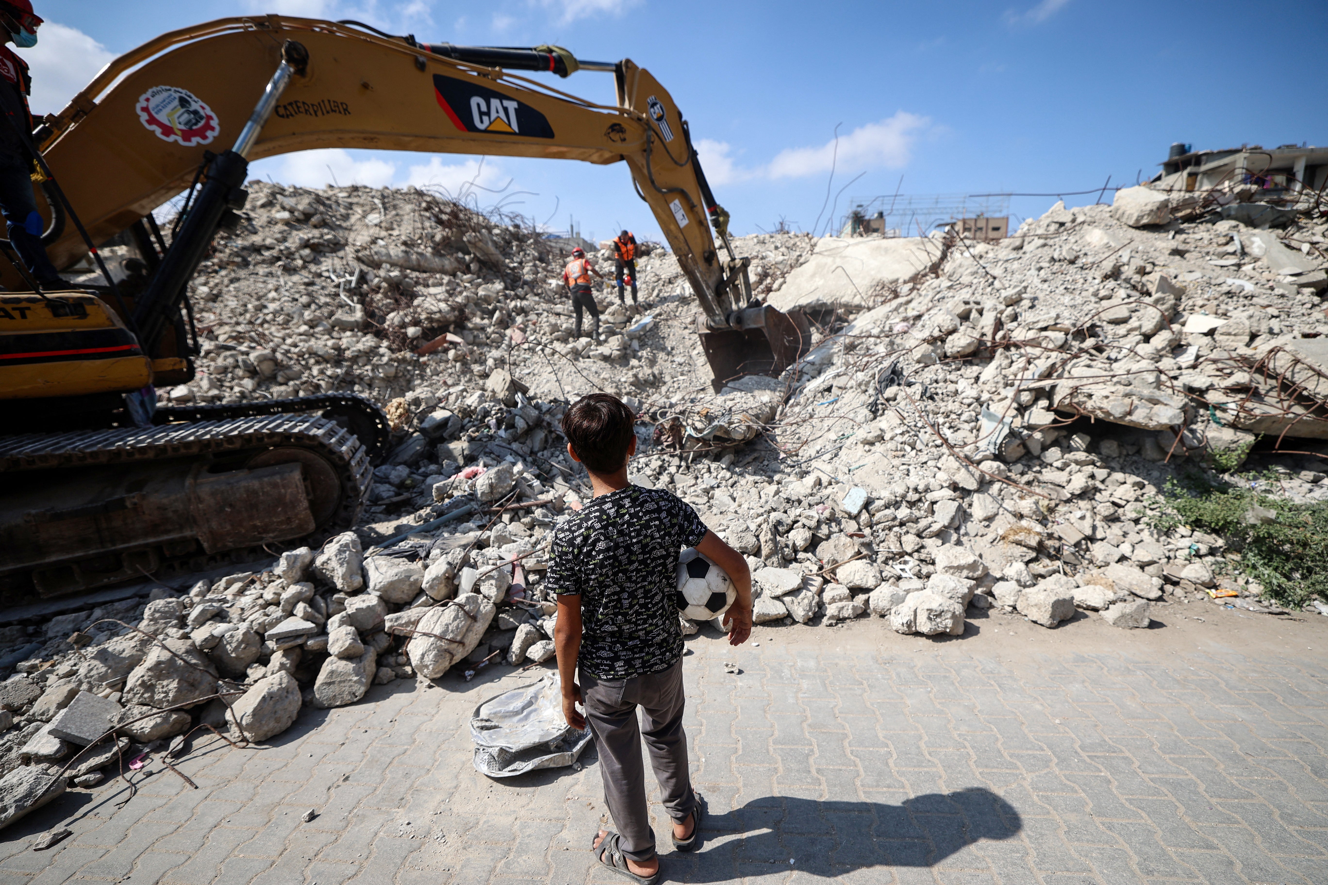 A young boy looks on as Civil Defence personnel dig through the rubble of Al-Muhandisin Tower, that was destroyed in israeli strikes in the early days of the war between Israel and Palestinian militant group Hamas, as they look for human remains in the Nuseirat camp for refugees in the central Gaza Strip on September 5, 2026.