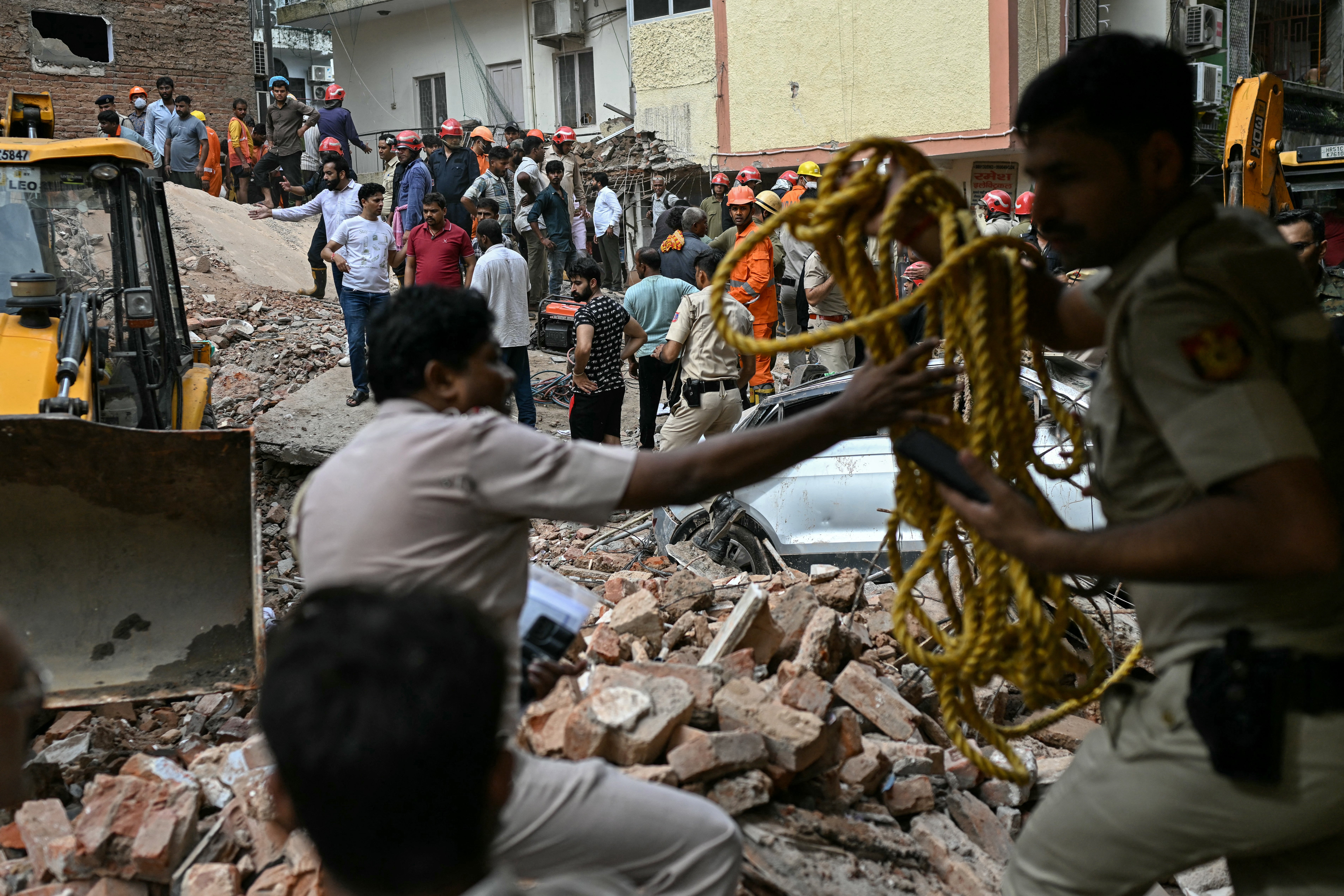 Security personnel cordon off the area as a bulldozer clears debris at the site following a building collapse in the Satya Niketan area in New Delhi (AFP/Getty)