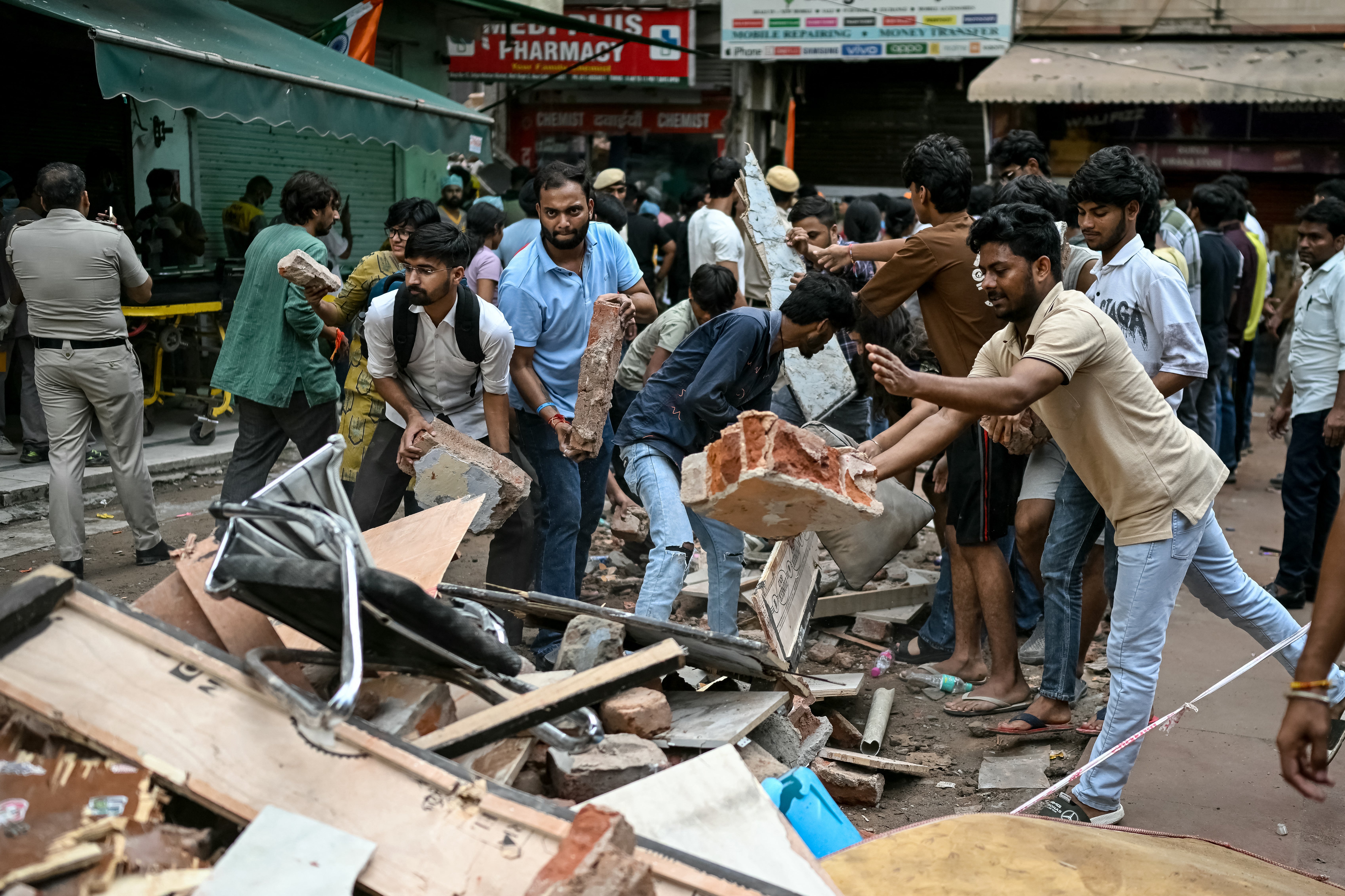 People clear debris as rescue personnel conduct a search operation for survivors at the site of a building collapse in the Satya Niketan area in New Delhi on 6 September 2026 (AFP/Getty)