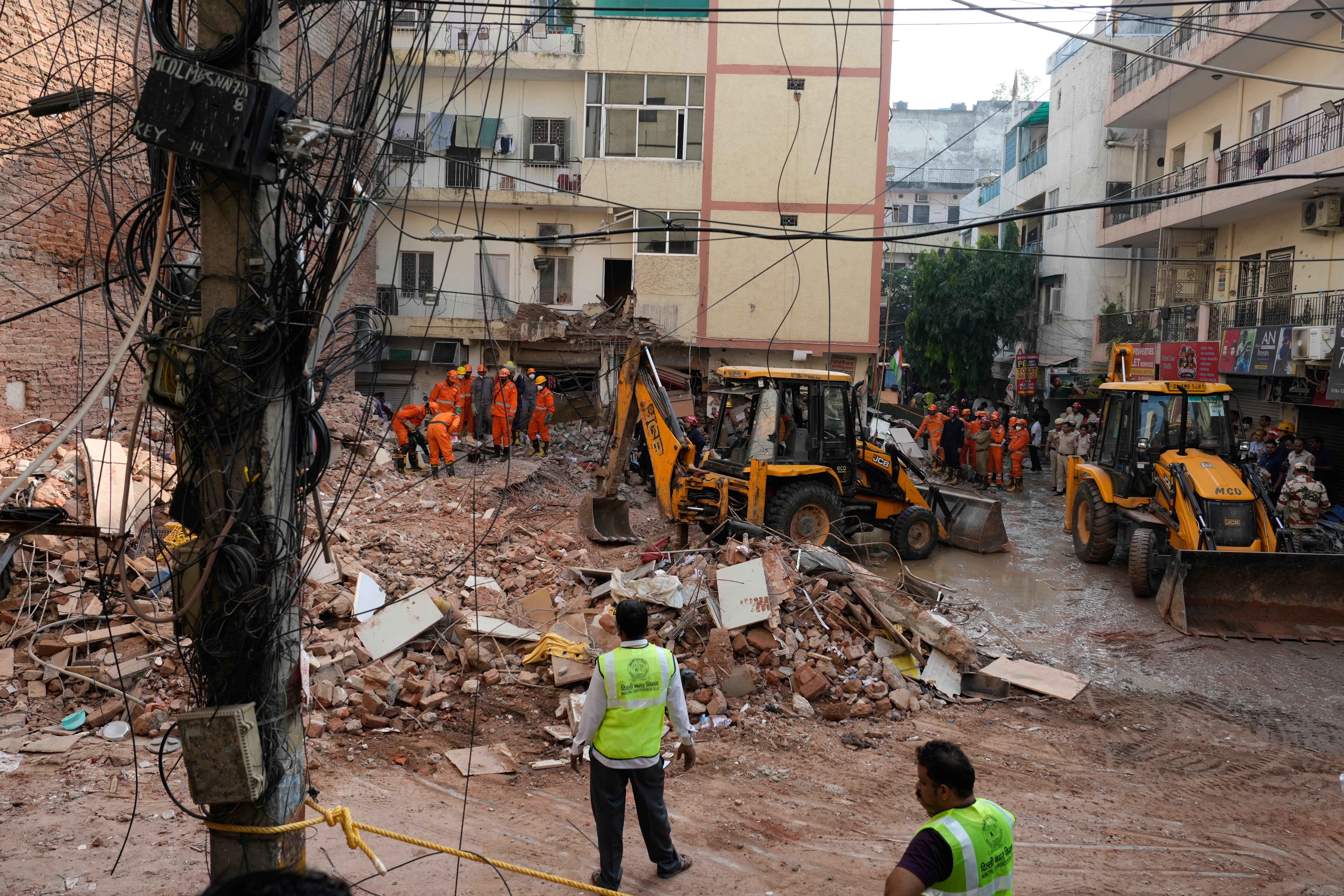 Rescuers clear debris as they search for people possibly trapped at the site of a collapsed building in Delhi, India
