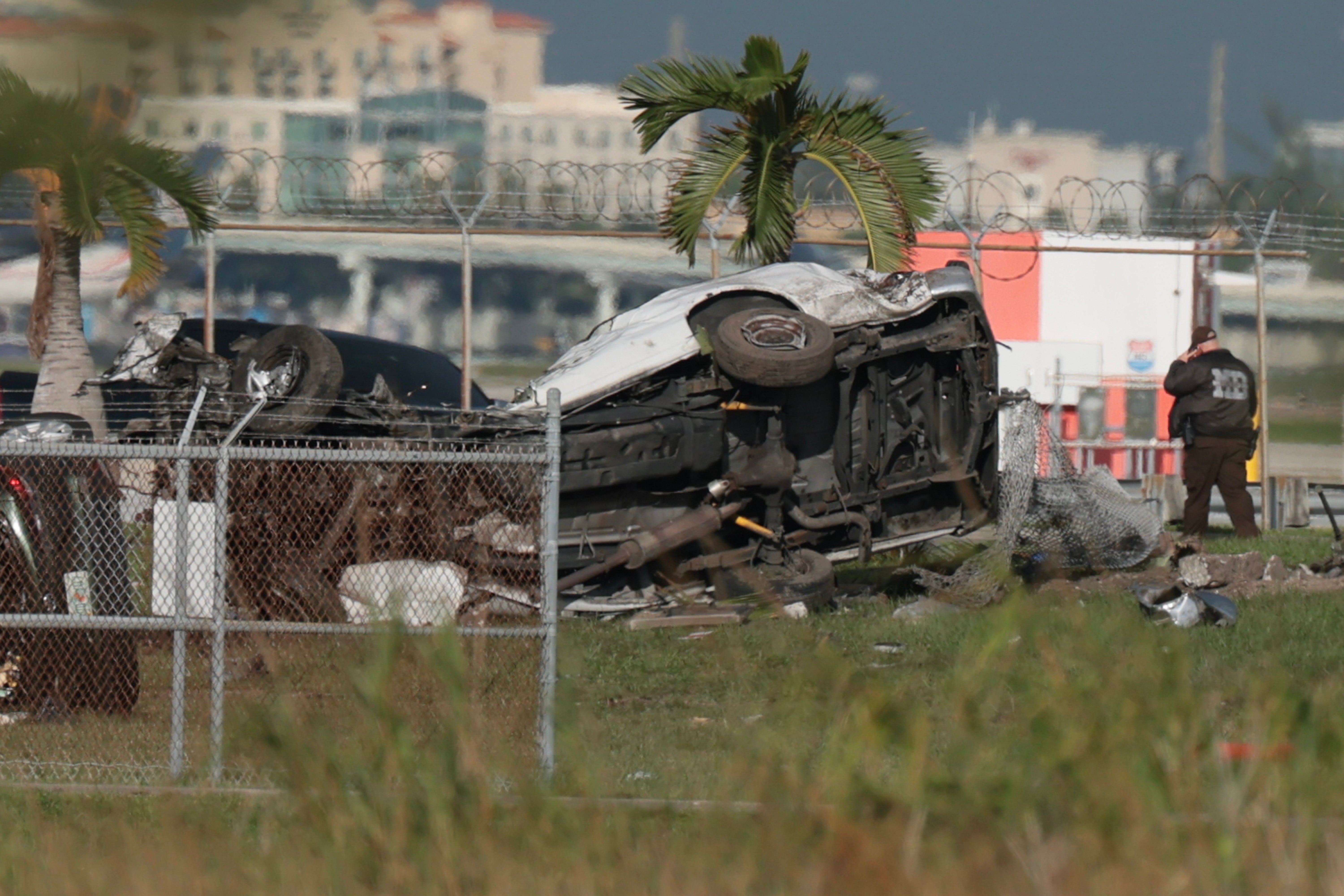 Investigators walk near damaged vehicles at Miami International Airport