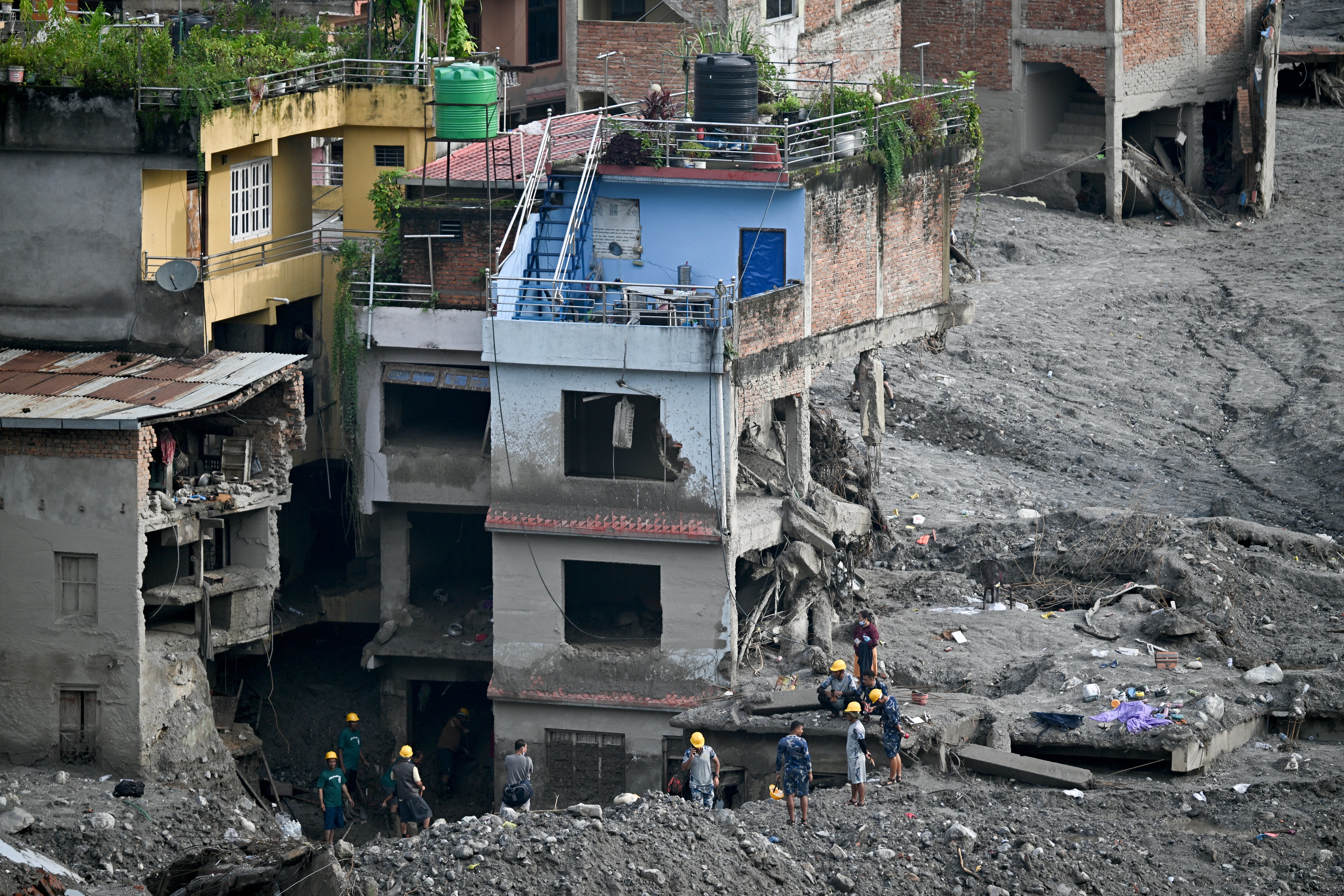 Relief and security personnel inspect a damaged house covered in sludge in the aftermath of flash floods at Trishuli in Nepal's Nuwakot district on 7 September 2026