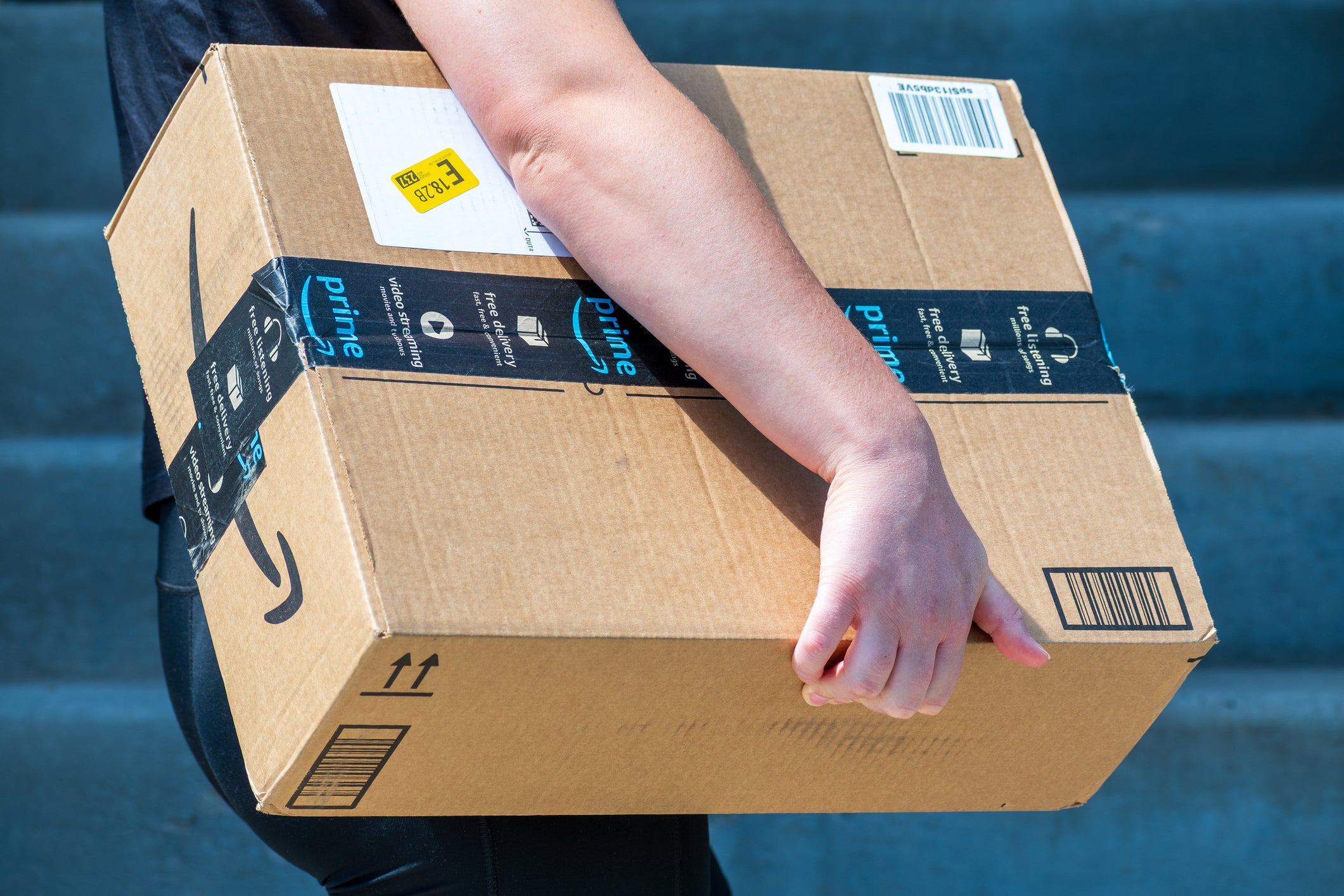An Amazon Flex driver delivers a large cardboard box to a residential doorstep.