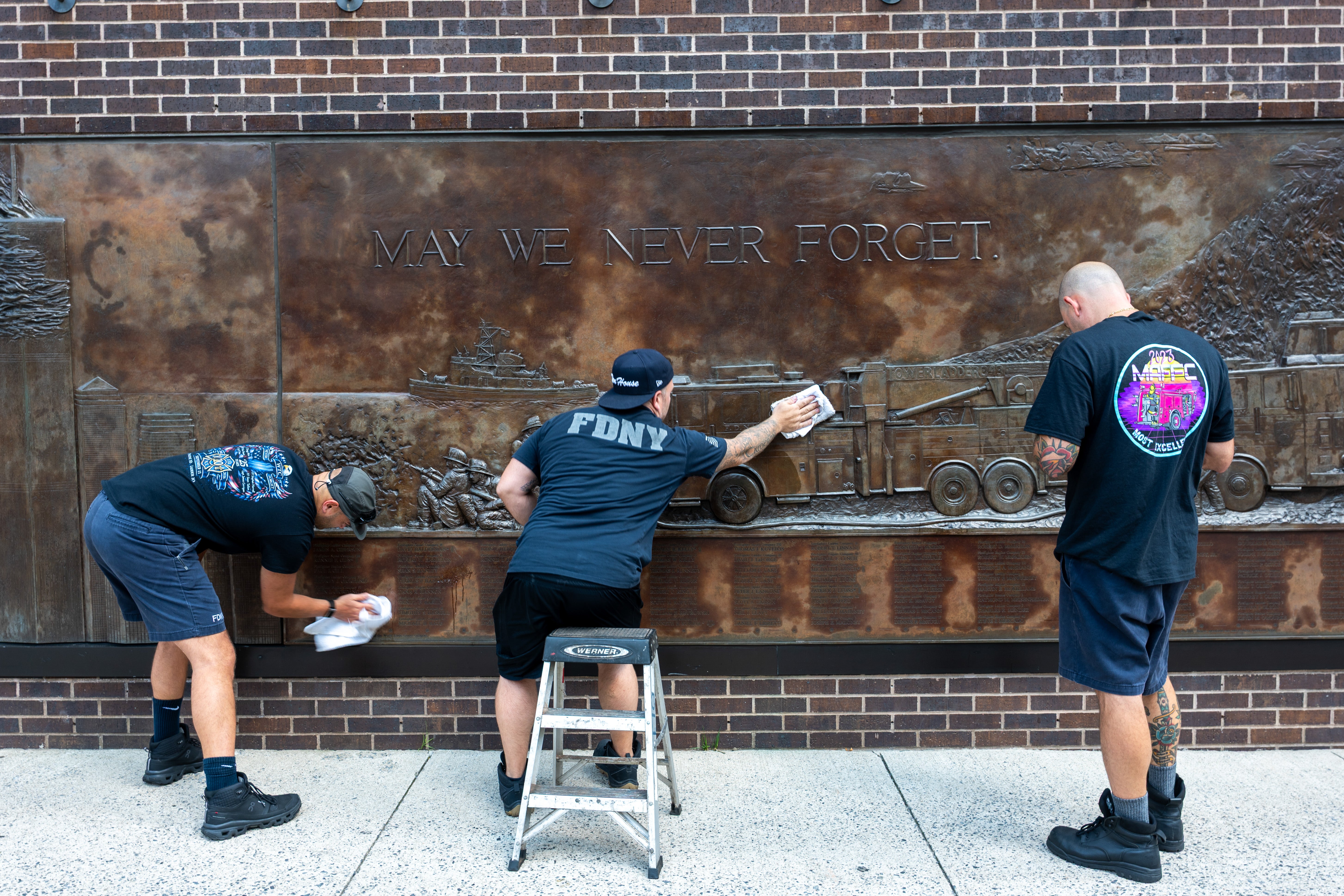 Firefighters polish a memorial to members of the FDNY lost on September 11, 2001 at a firehouse across from the original site of the Twin Towers