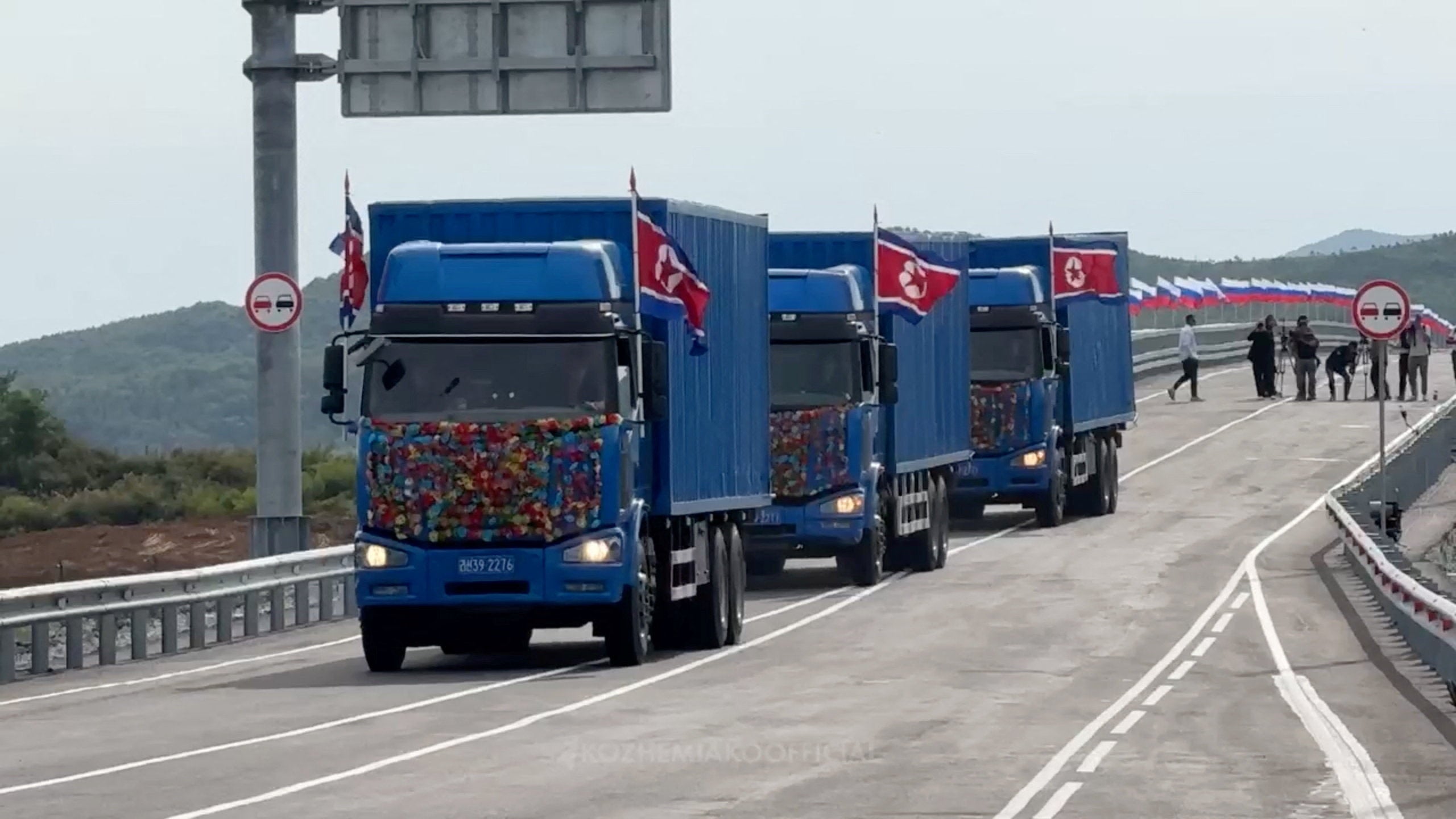 Trucks drive along a road during a ceremony opening the first road bridge between Russia and North Korea across the Tumen River