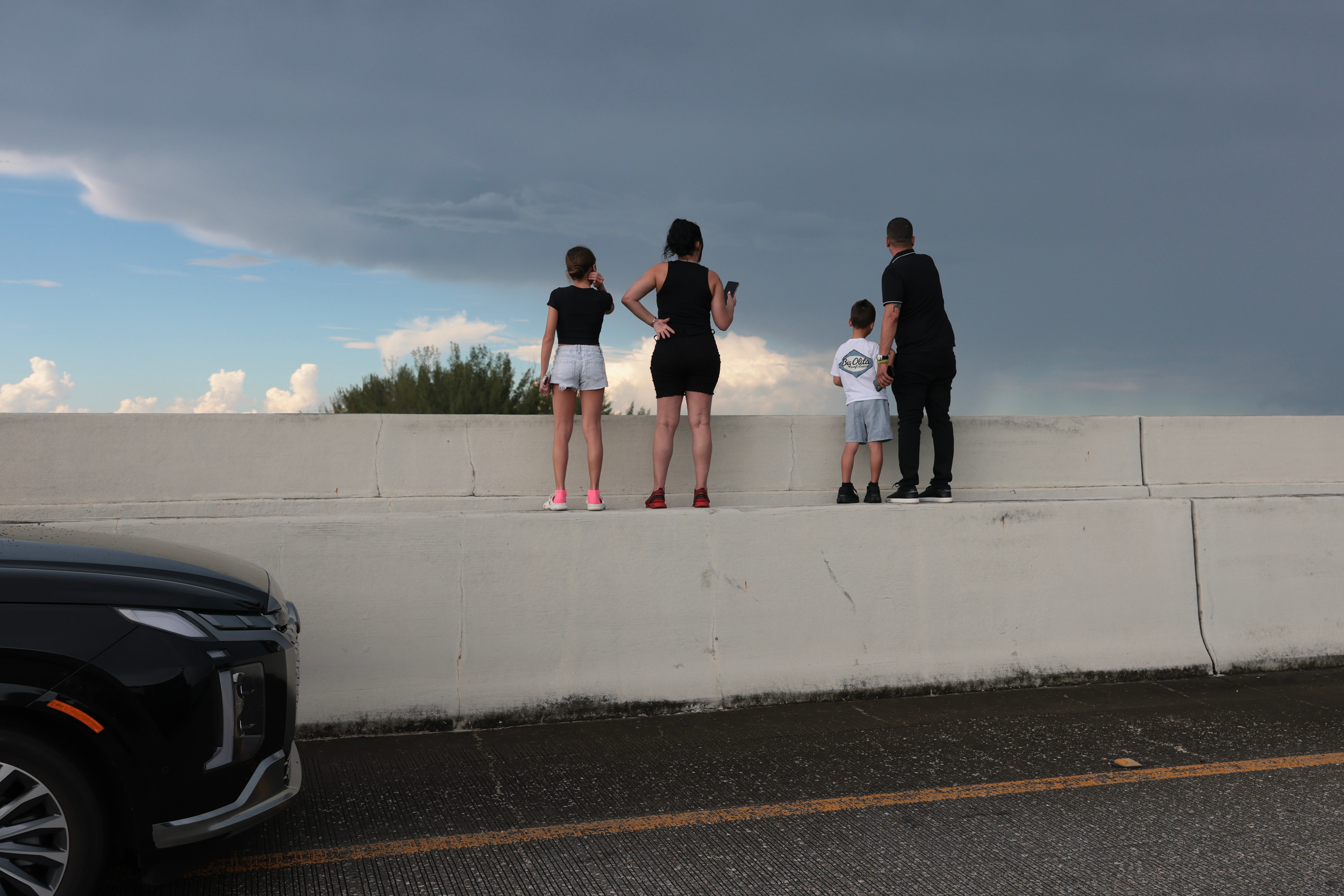 People stand on a median to look out at the wreckage caused by the crash
