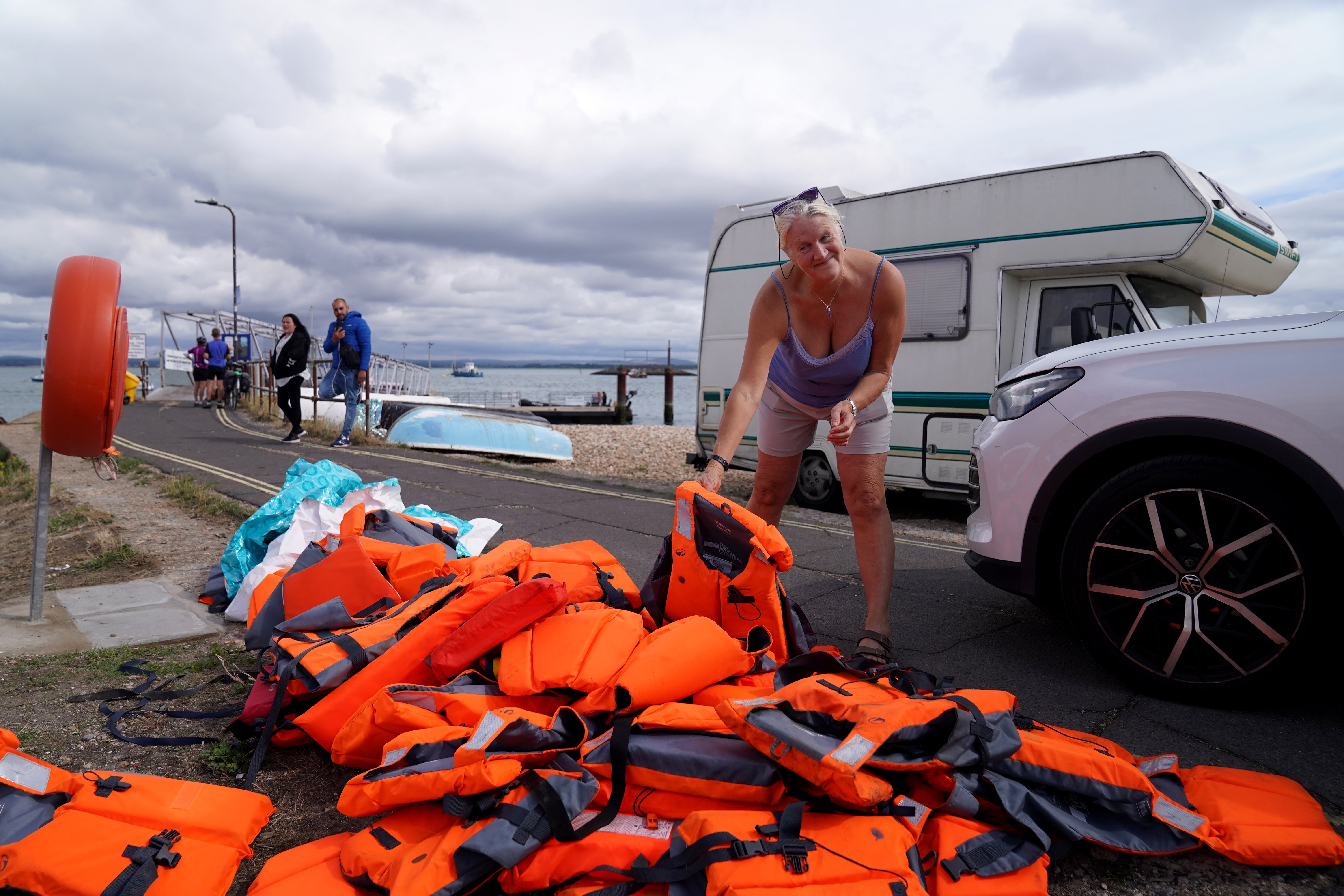 Local resident Sue Dewey, 68, collects some of the discarded life jackets following Sunday night's operation in Portsmouth. Local leaders say the city is not suited for such landings.
