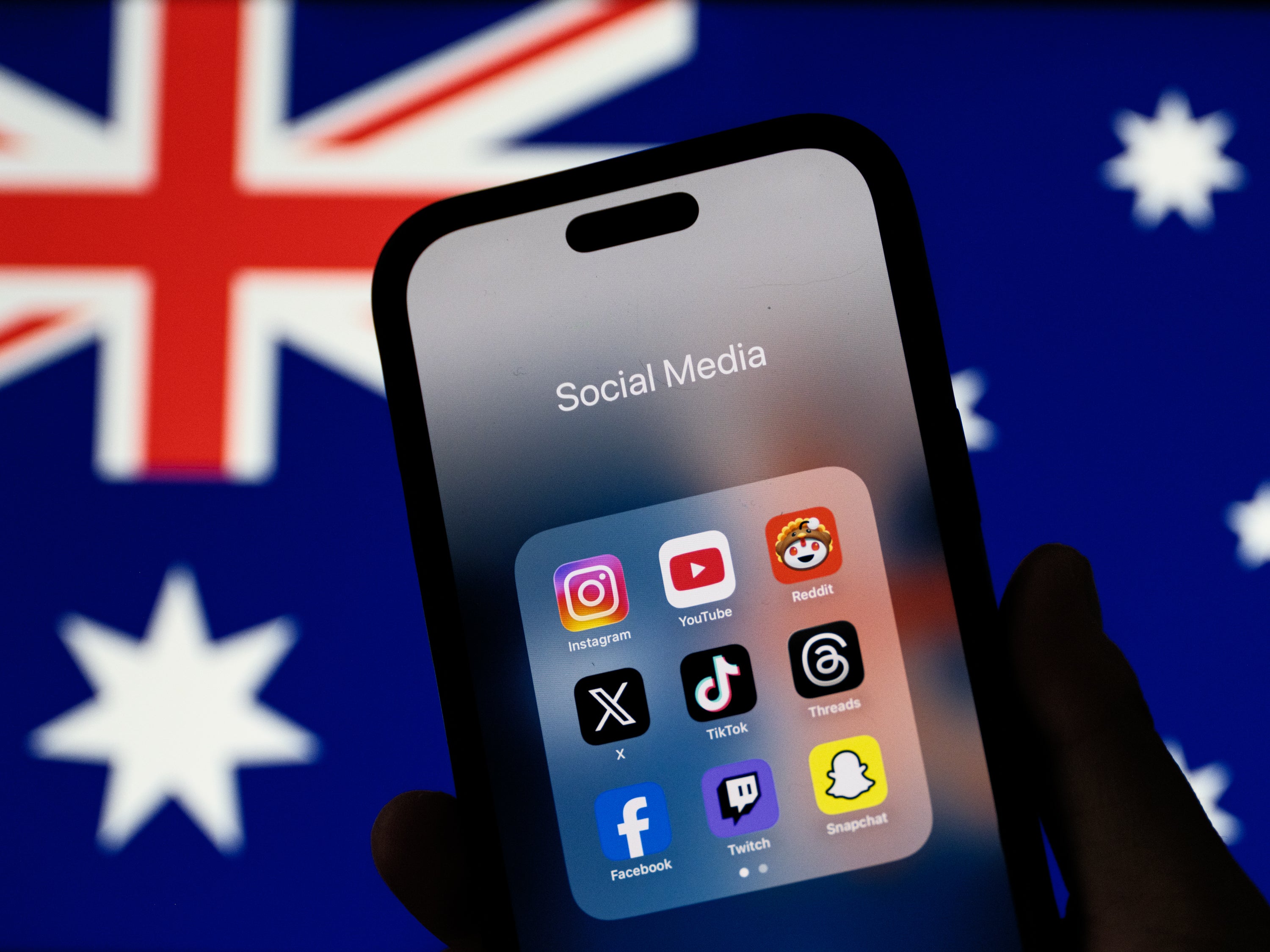 Social media networking apps are displayed on a phone screen with the Australian flag displayed in the background