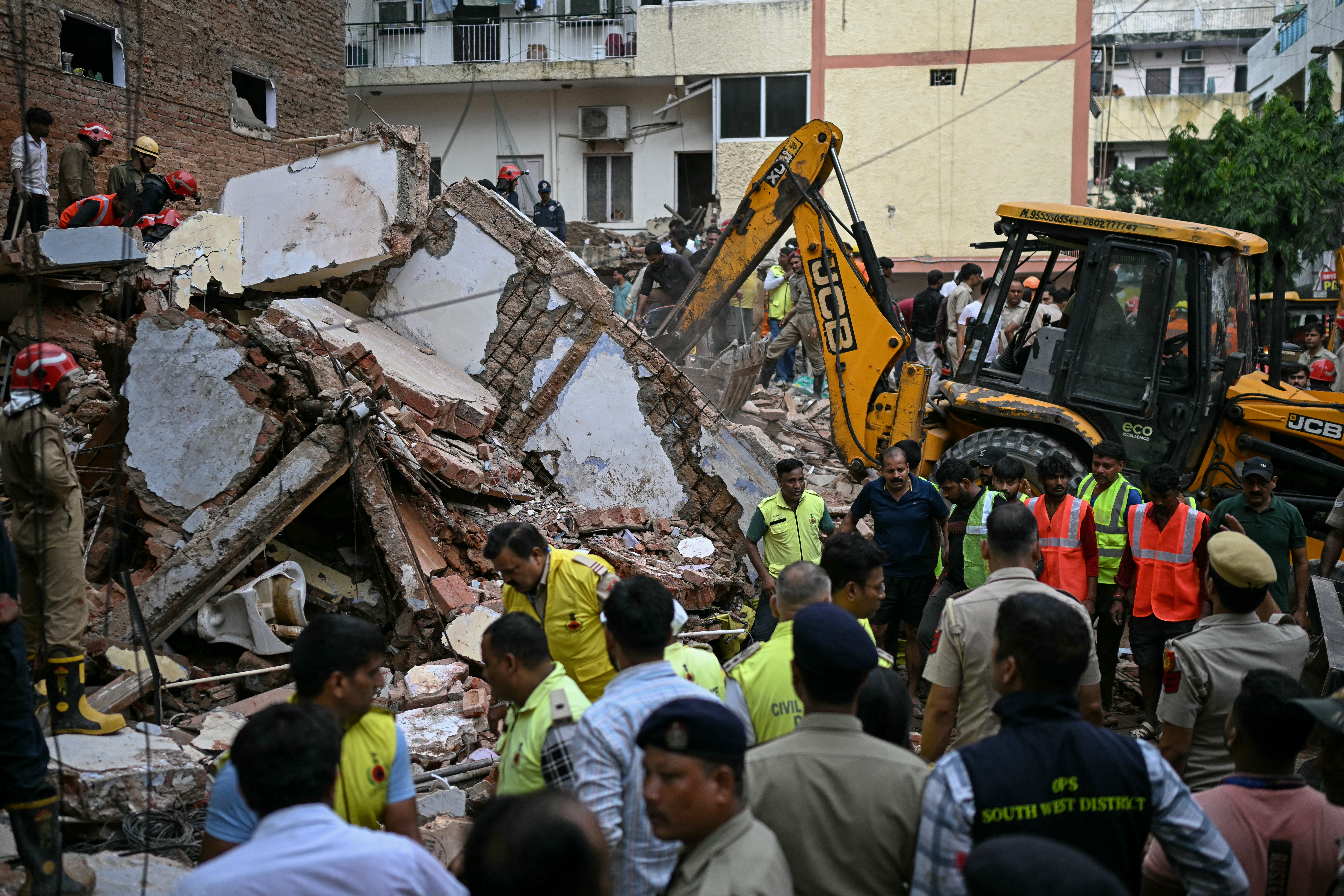 Bulldozers clear debris as rescue workers conduct a search at the site of the collapse