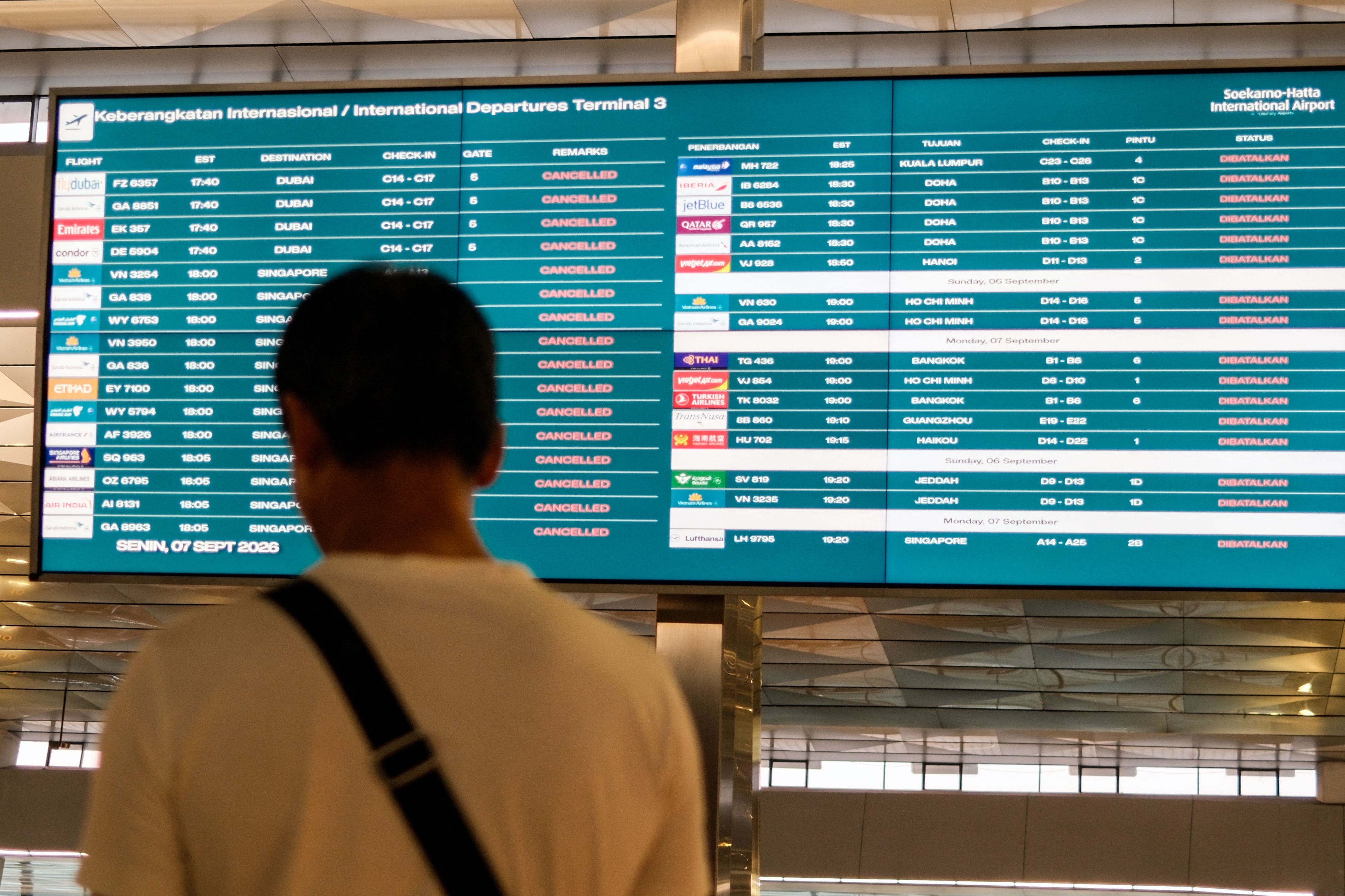 <p>A stranded passenger looks at a flight information screen at the Soekarno-Hatta airport</p>