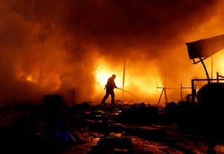 A firefighter works at the site of a private enterprise hit during Russian missile and drone strikes in Kyiv