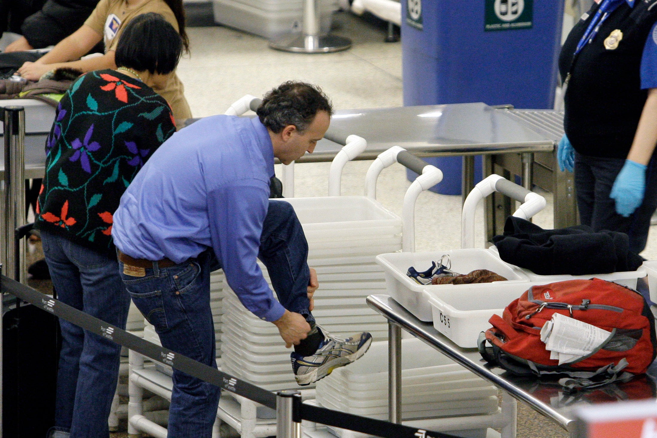 An airline passenger pulls off his shoes to be scanned as he prepares to go through a security checkpoint at Seattle-Tacoma International Airport