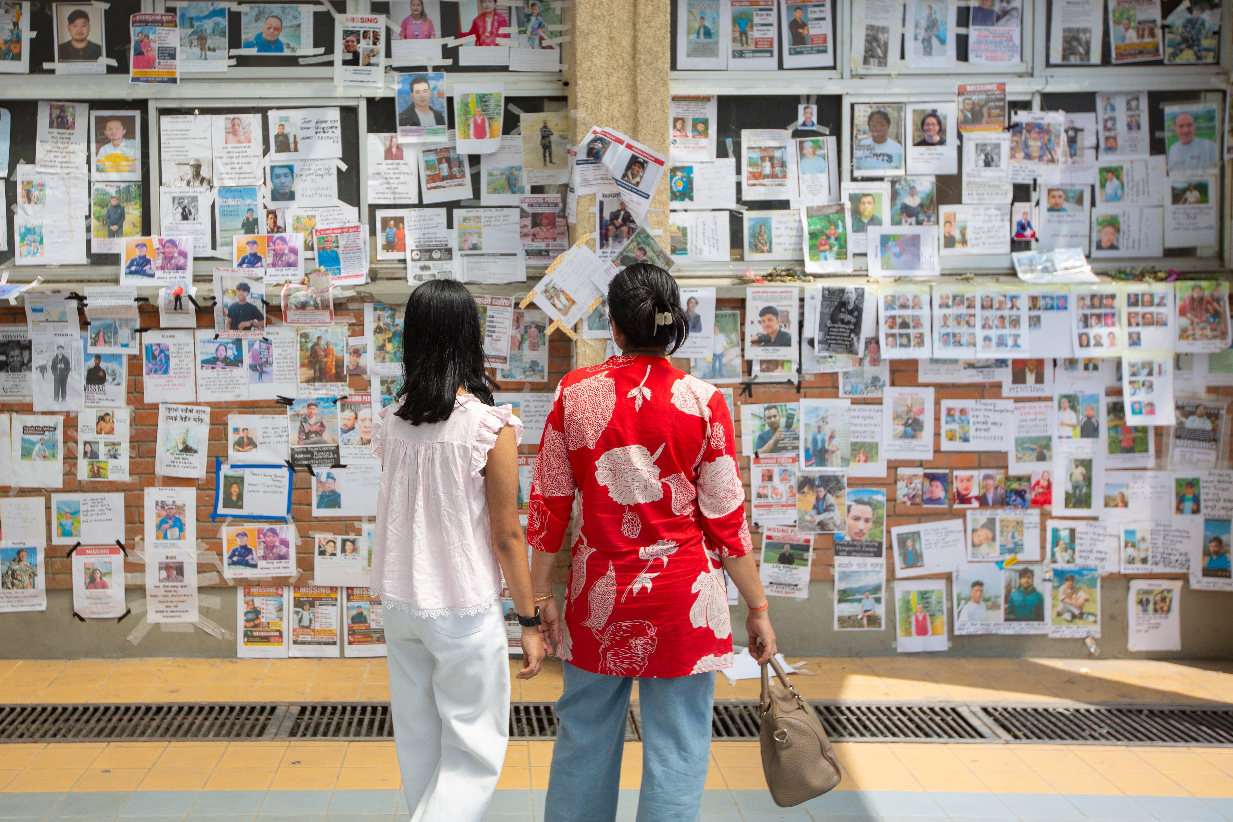 A wall covered with photographs of people reported missing after the recent floods in Nepal