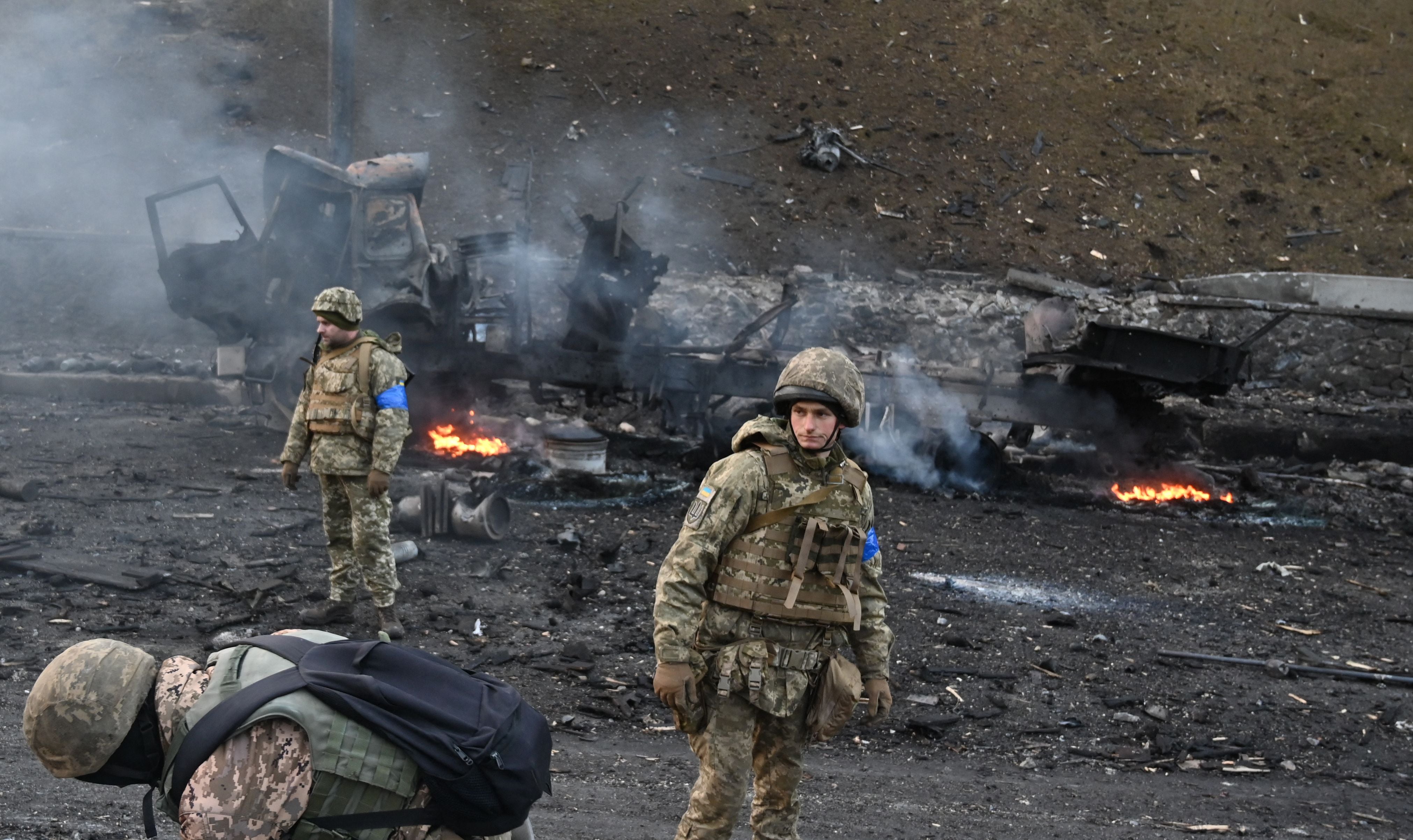 Ukrainian service members look for and collect unexploded shells after a fighting with Russian raiding group in the Ukrainian capital of Kyiv in the morning of February 26, 2022